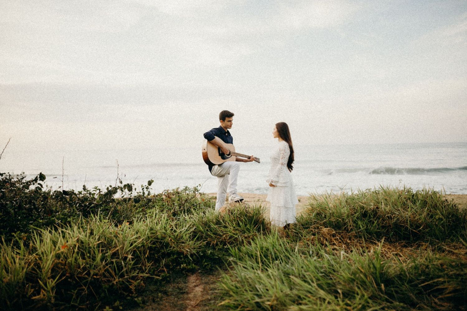 A romantic seaside photoshoot with a couple in contrasting navy and white outfits.