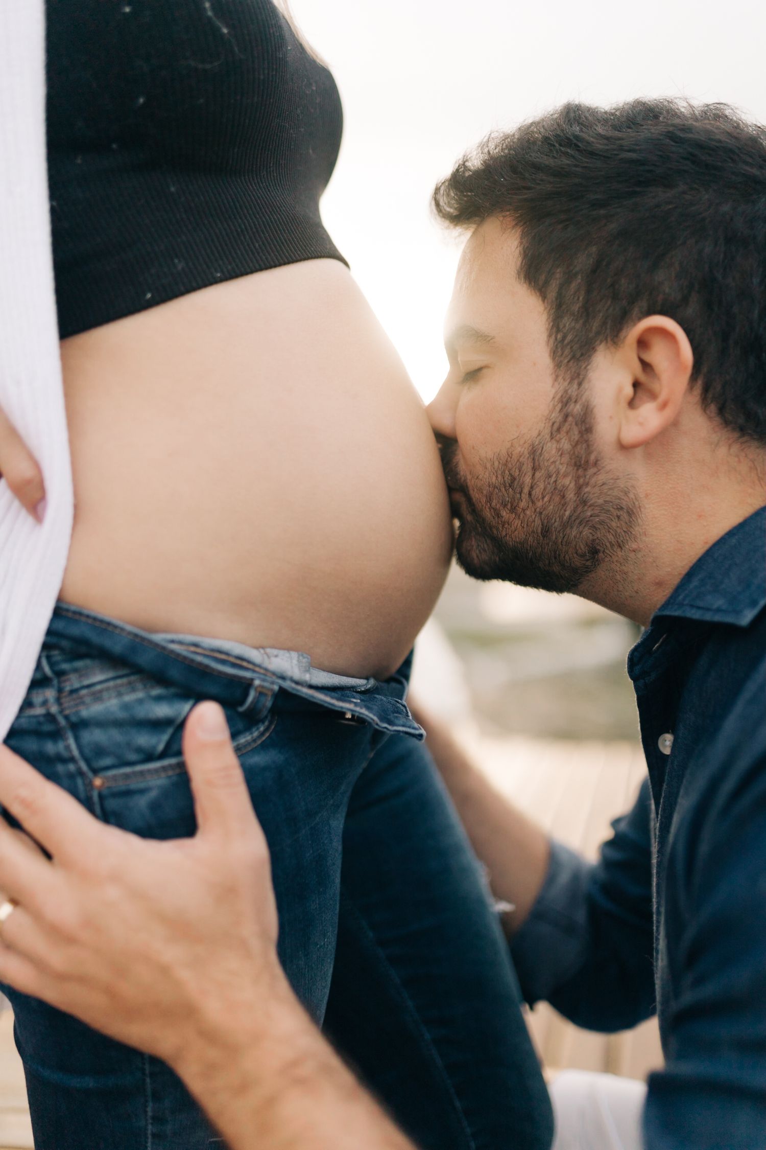An intimate maternity photo showing a tender moment with a pregnant belly.