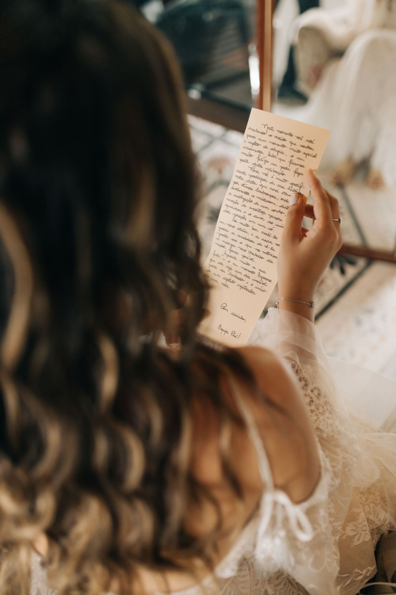 A handwritten letter being read on a wedding morning with curled hair and lace dress visible.