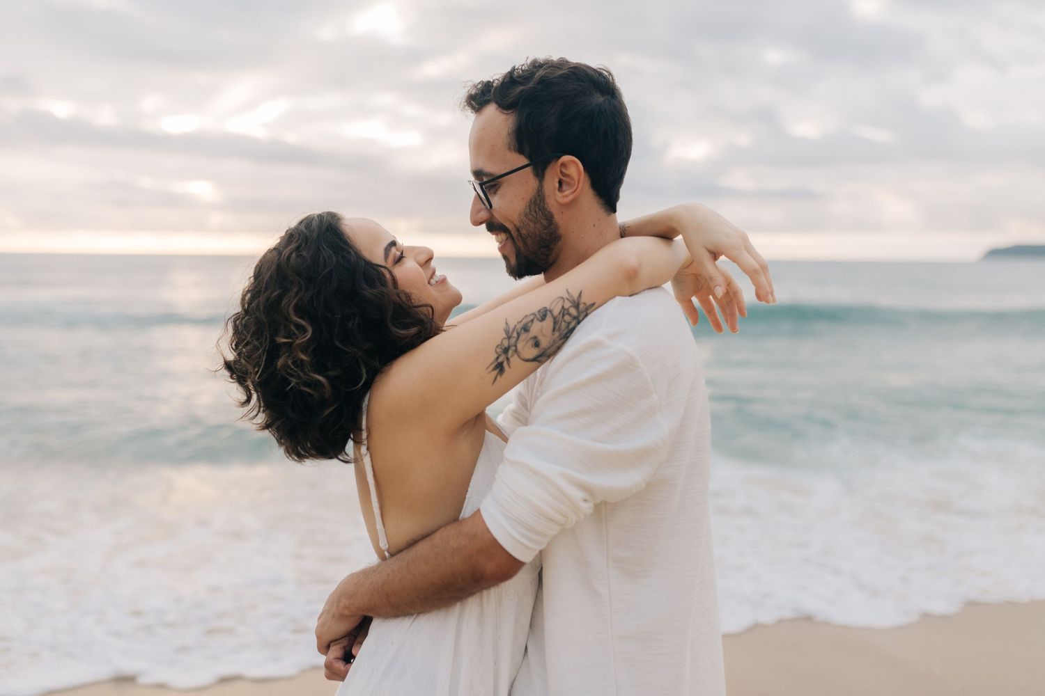 A romantic beach embrace with waves rolling in the background.