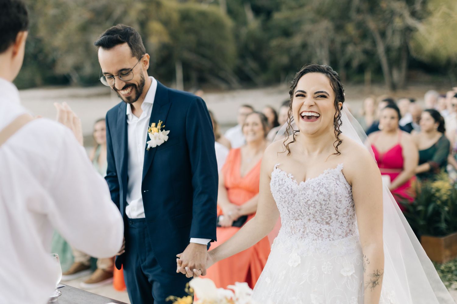 Joyful moment captured during outdoor wedding ceremony with guests in background.