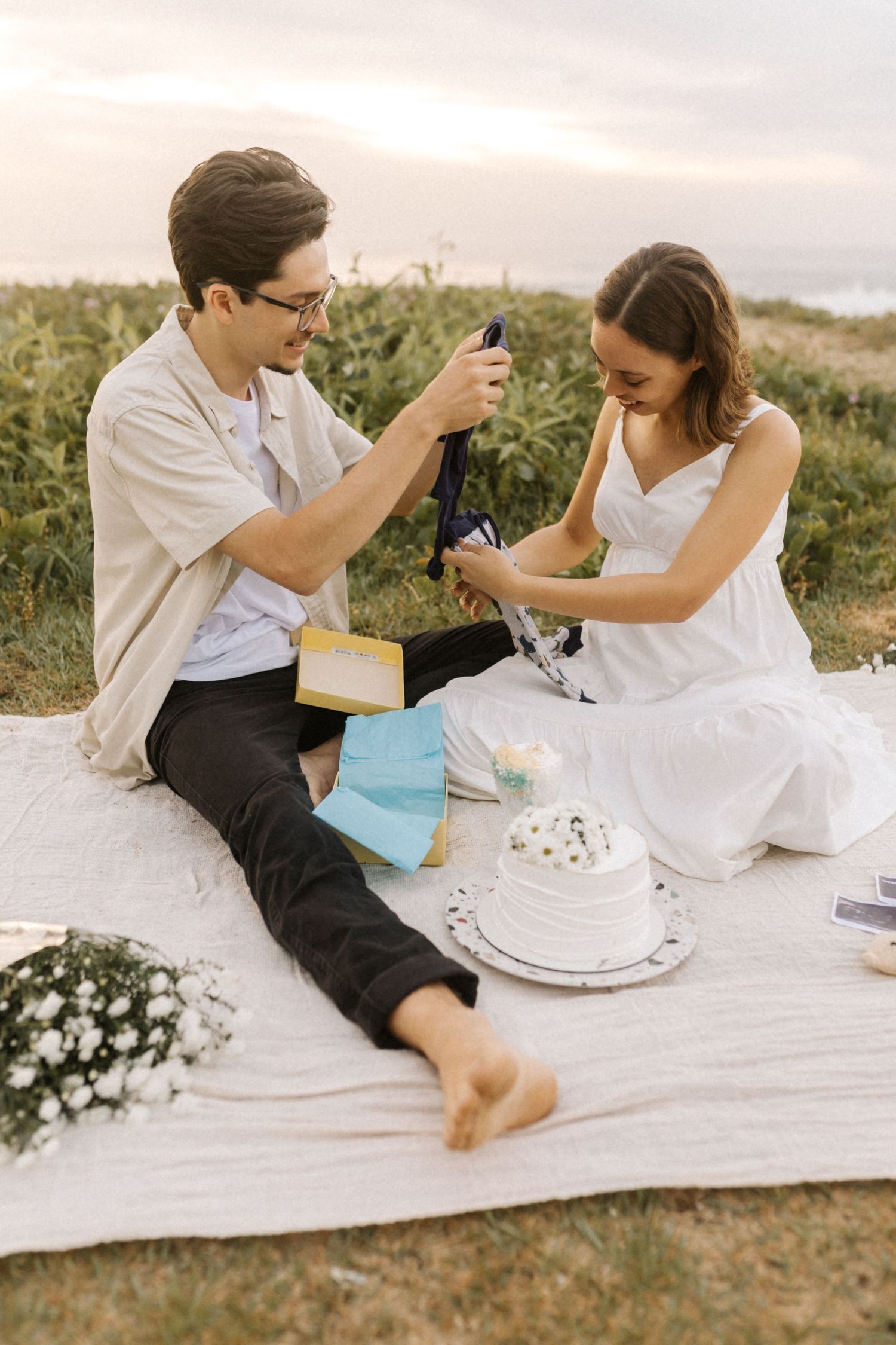 Two people having fun on a picnic blanket with cake and playful cake smashing moments outdoors.