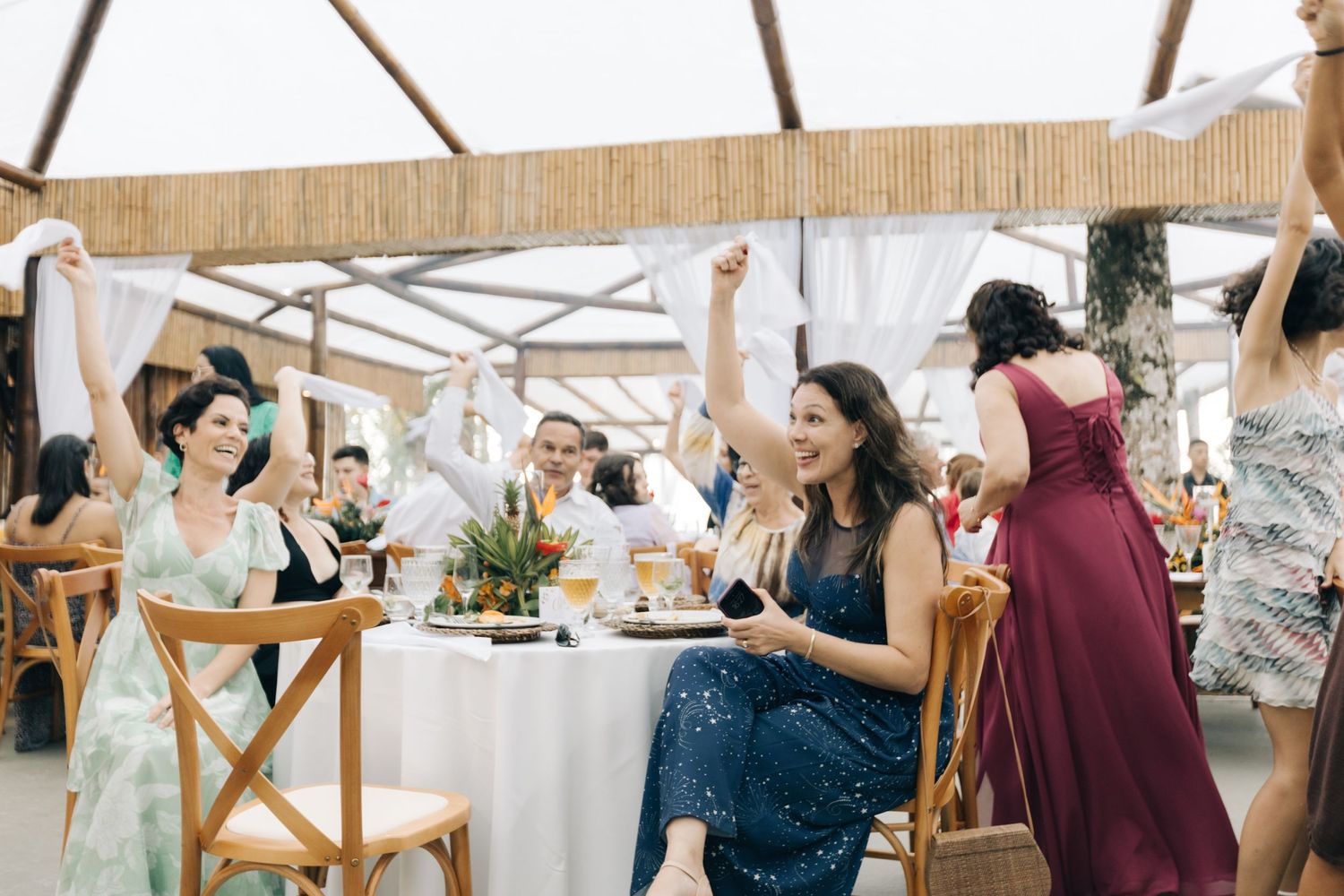Wedding reception guests enjoying conversation at decorated outdoor venue.