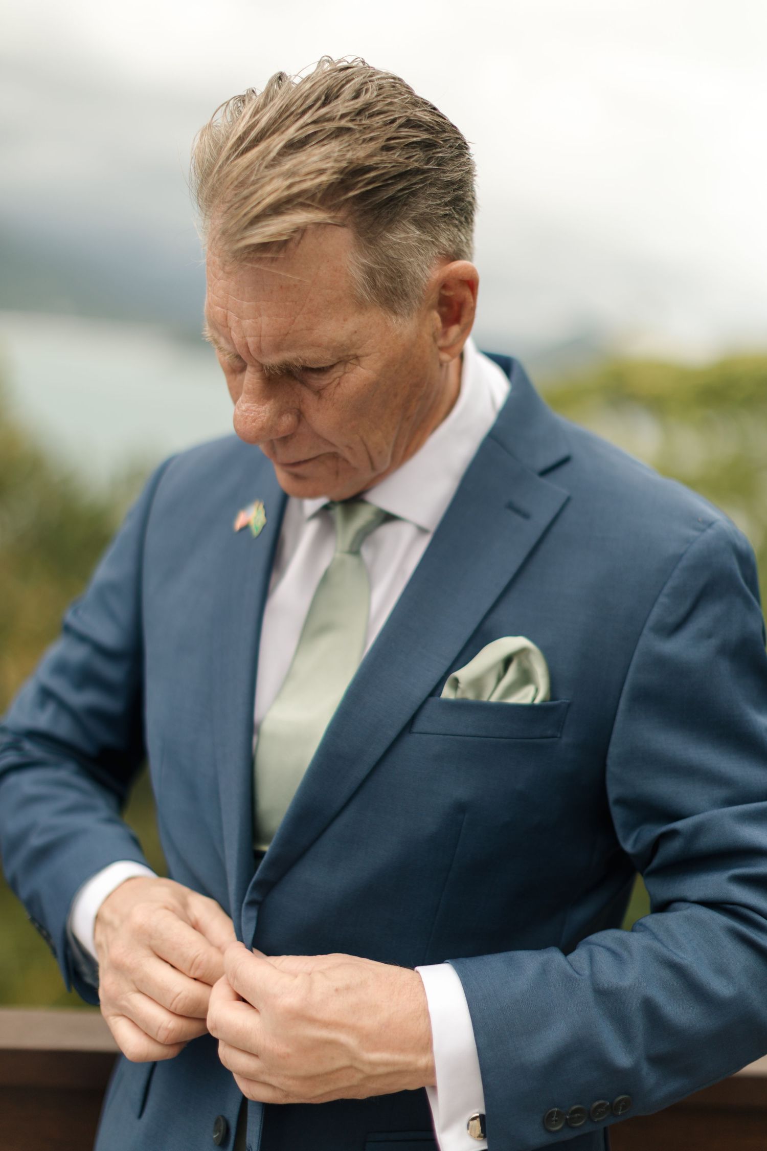 Close-up sequence showing a person in a navy suit adjusting their pocket square and tie before an event.