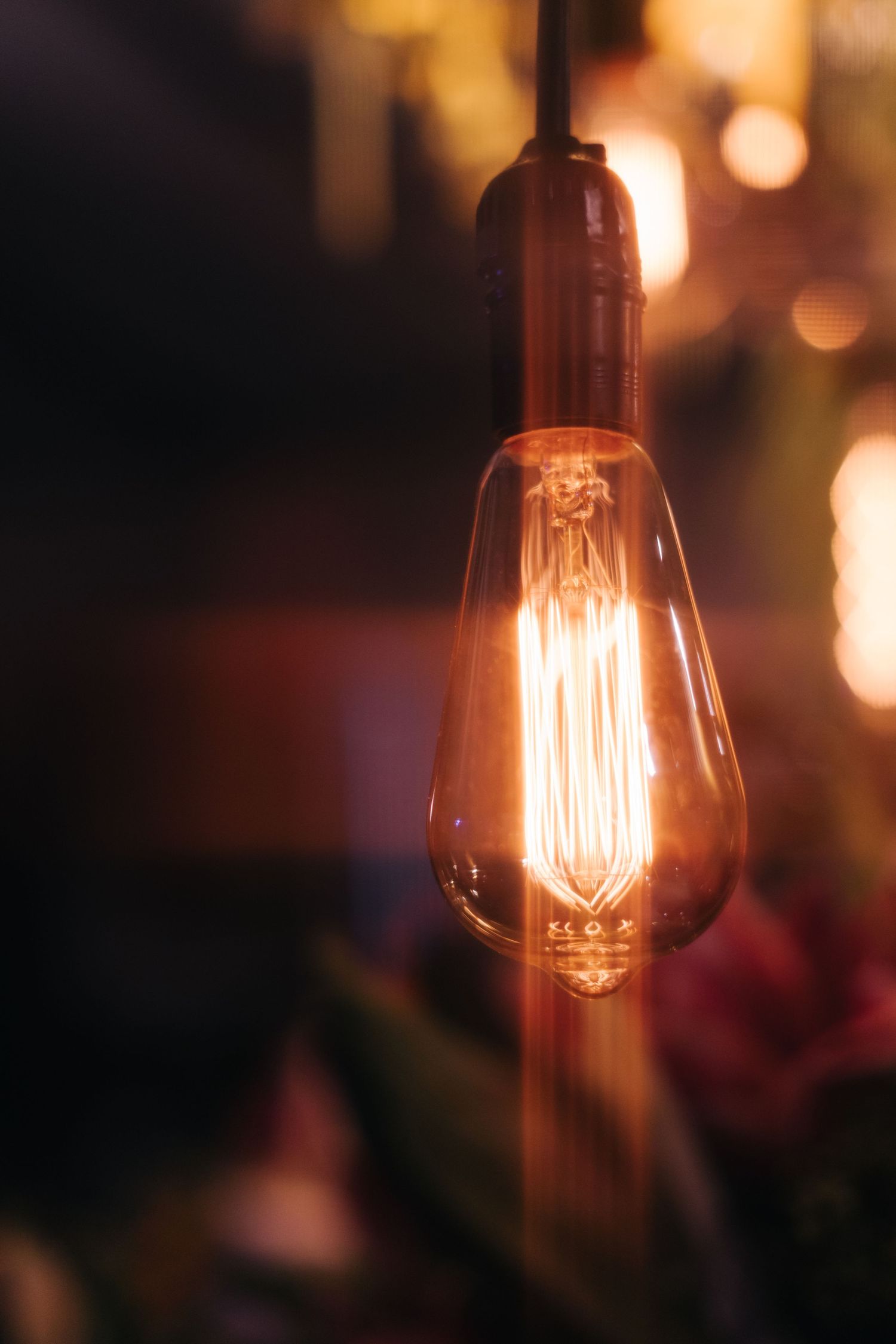 Vintage Edison light bulb glowing warmly in a dark setting.