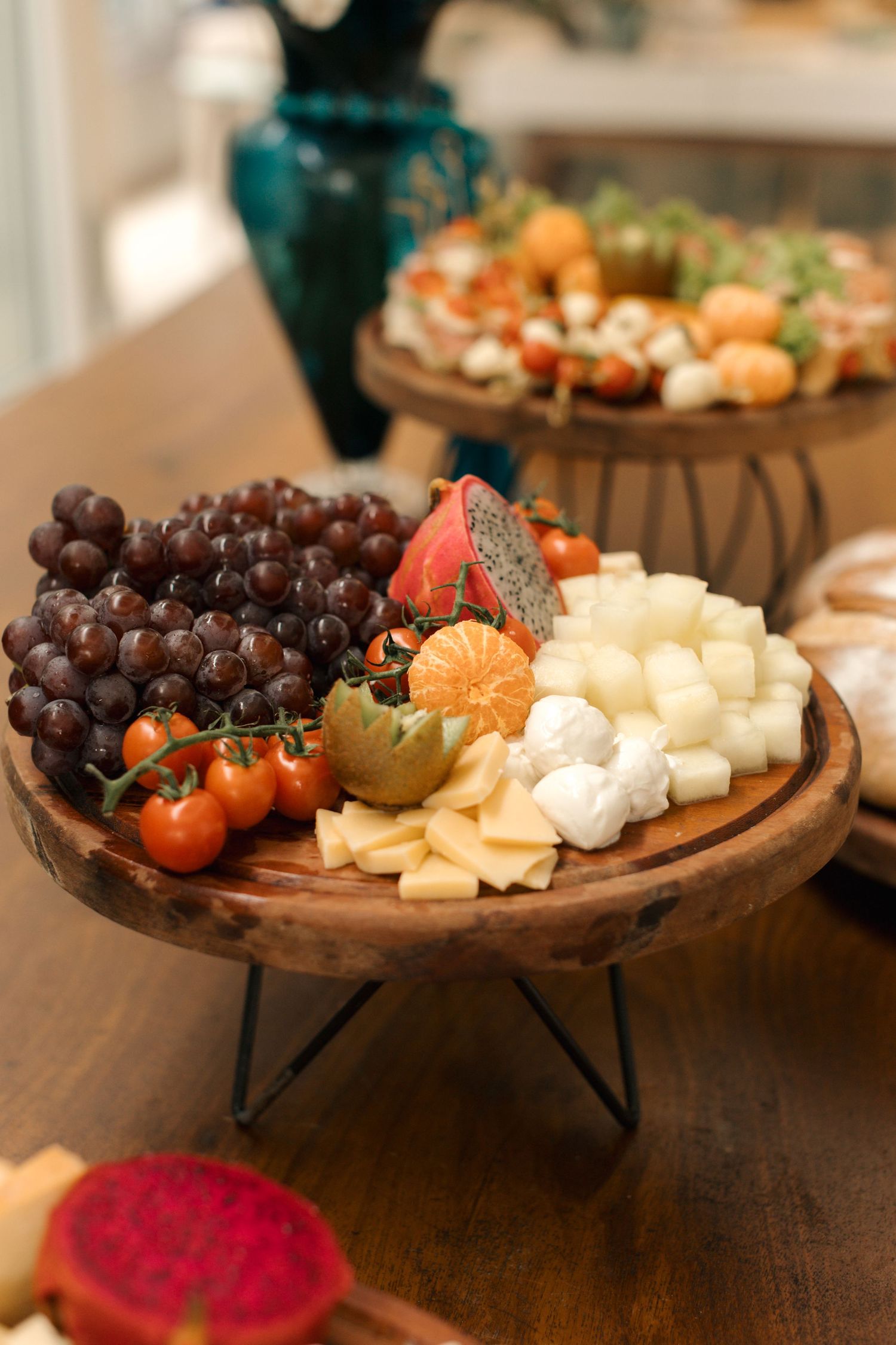 Artfully arranged charcuterie board with grapes, cheese, and tomatoes on wooden platter.