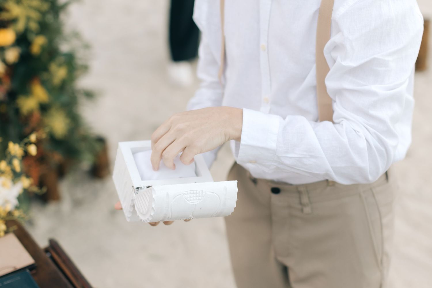 Close-up of hands holding white paper cup during outdoor event.