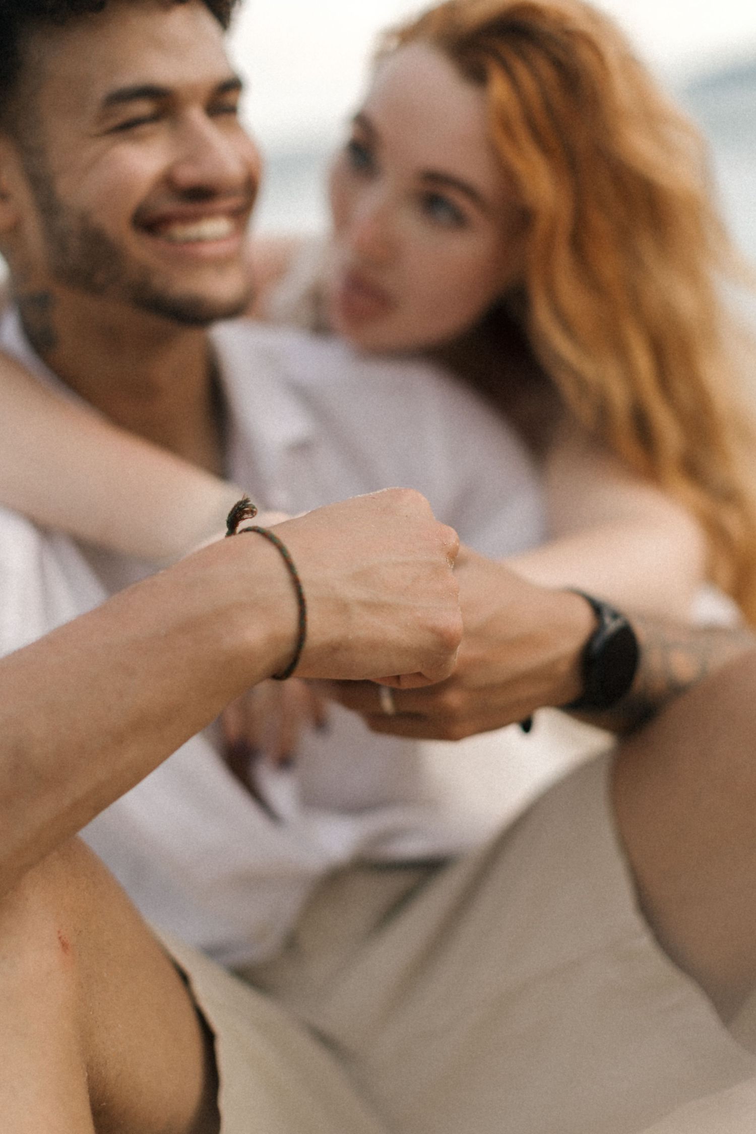 Couple holding hands wearing matching black bracelets in a tender close-up moment.