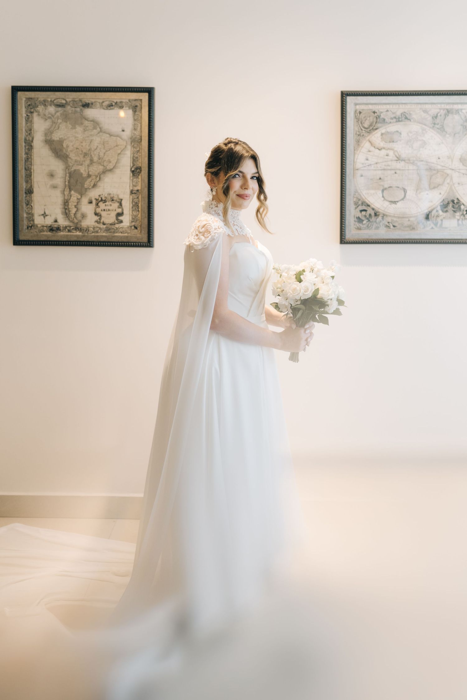 Classic bridal portrait featuring flowing white gown and bouquet with antique maps in background.