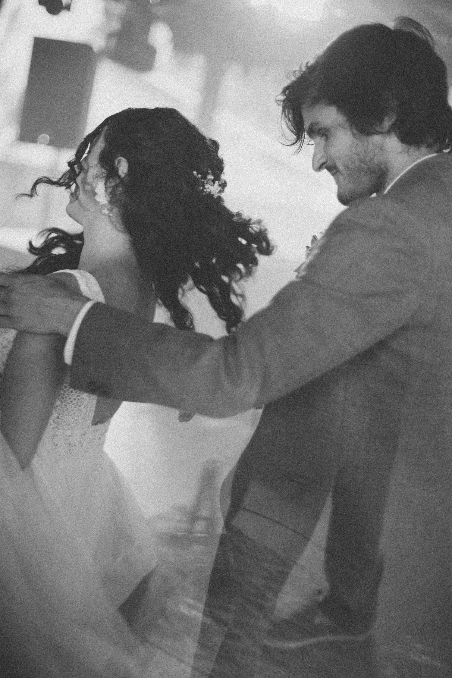 Black and white image shows dancing couples in an intimate reception moment.