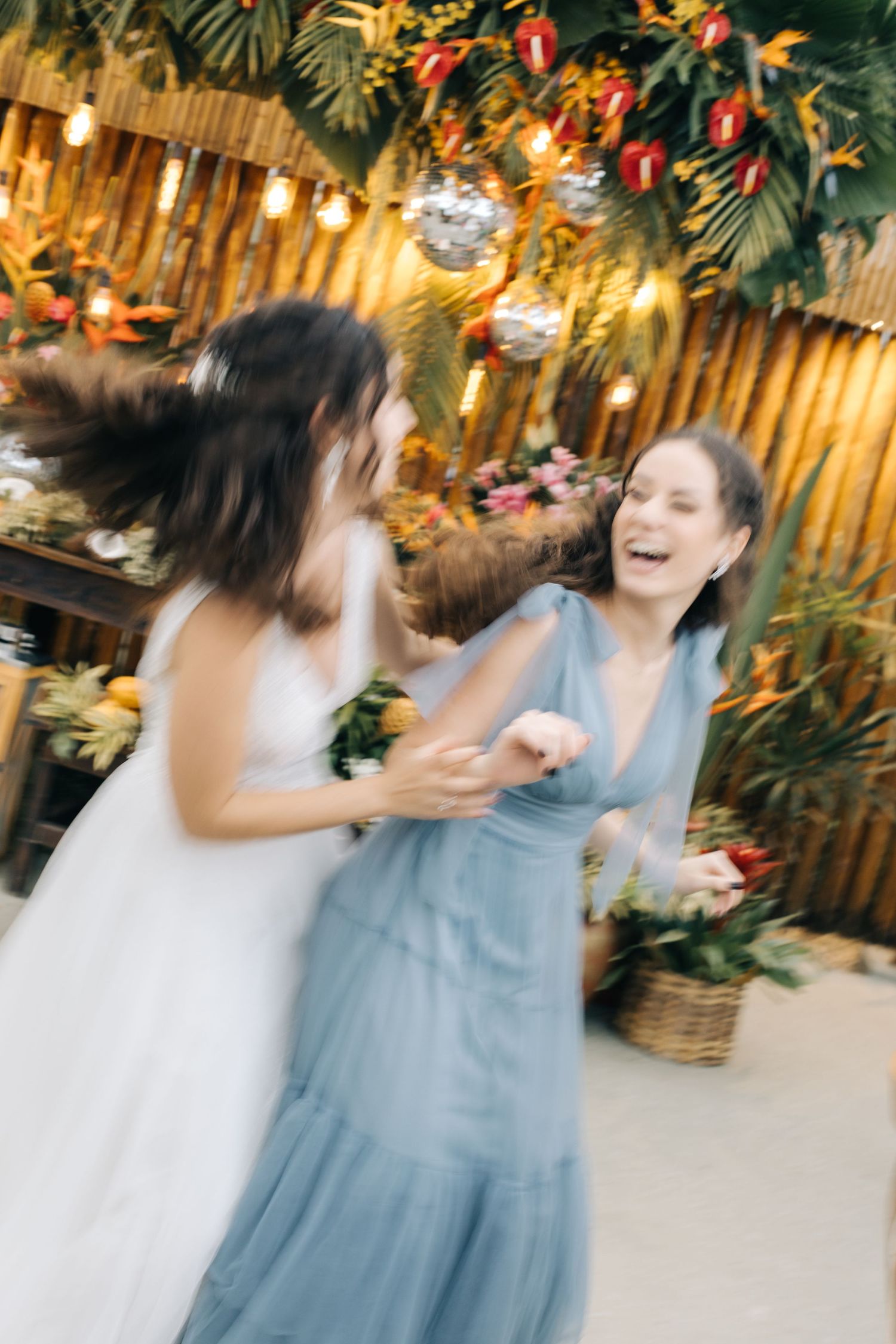 Motion-blurred photo of wedding celebration with tropical decor and disco balls.