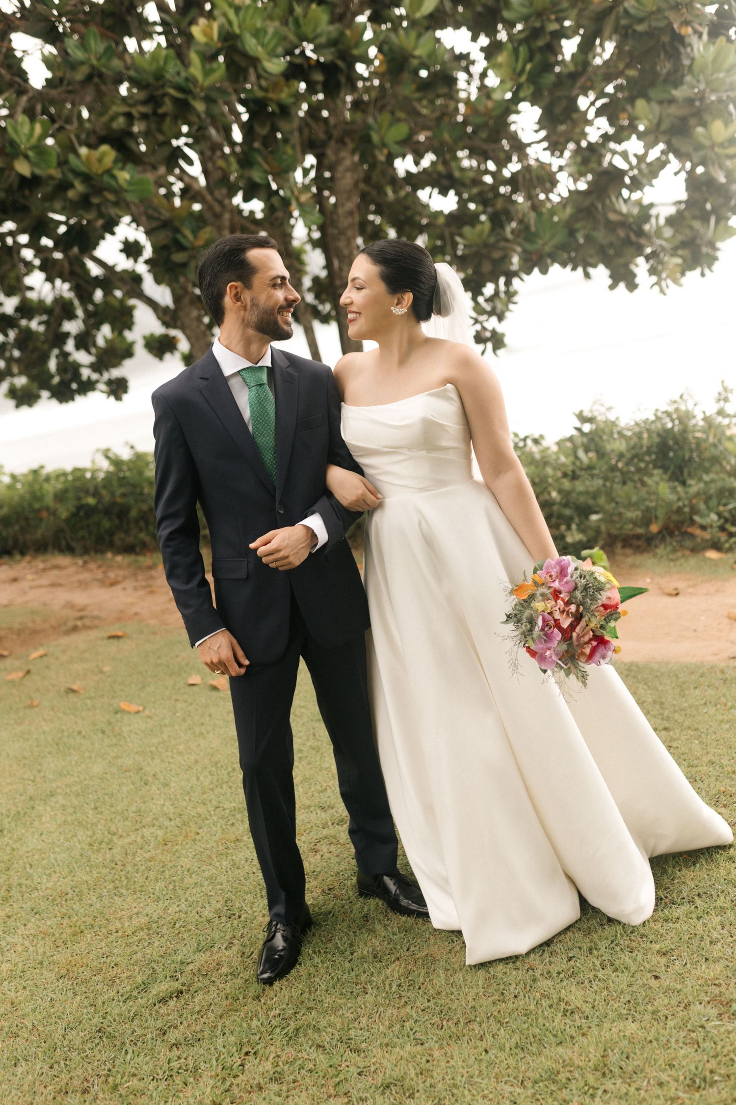 Newlyweds walking together on grass during outdoor photo session.