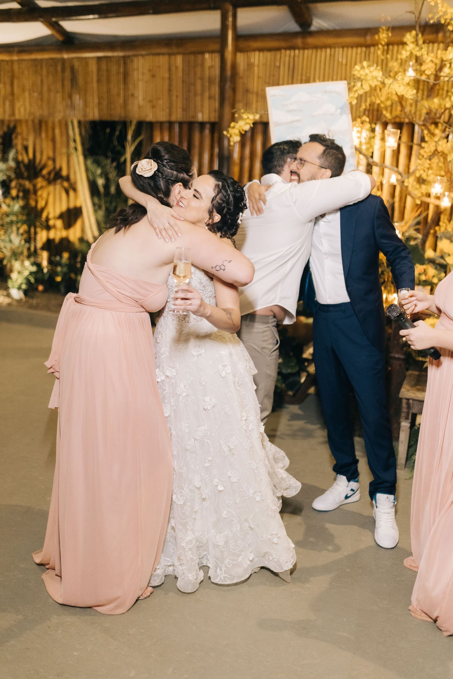 Wedding party dancing together in a rustic venue decorated with warm lighting.