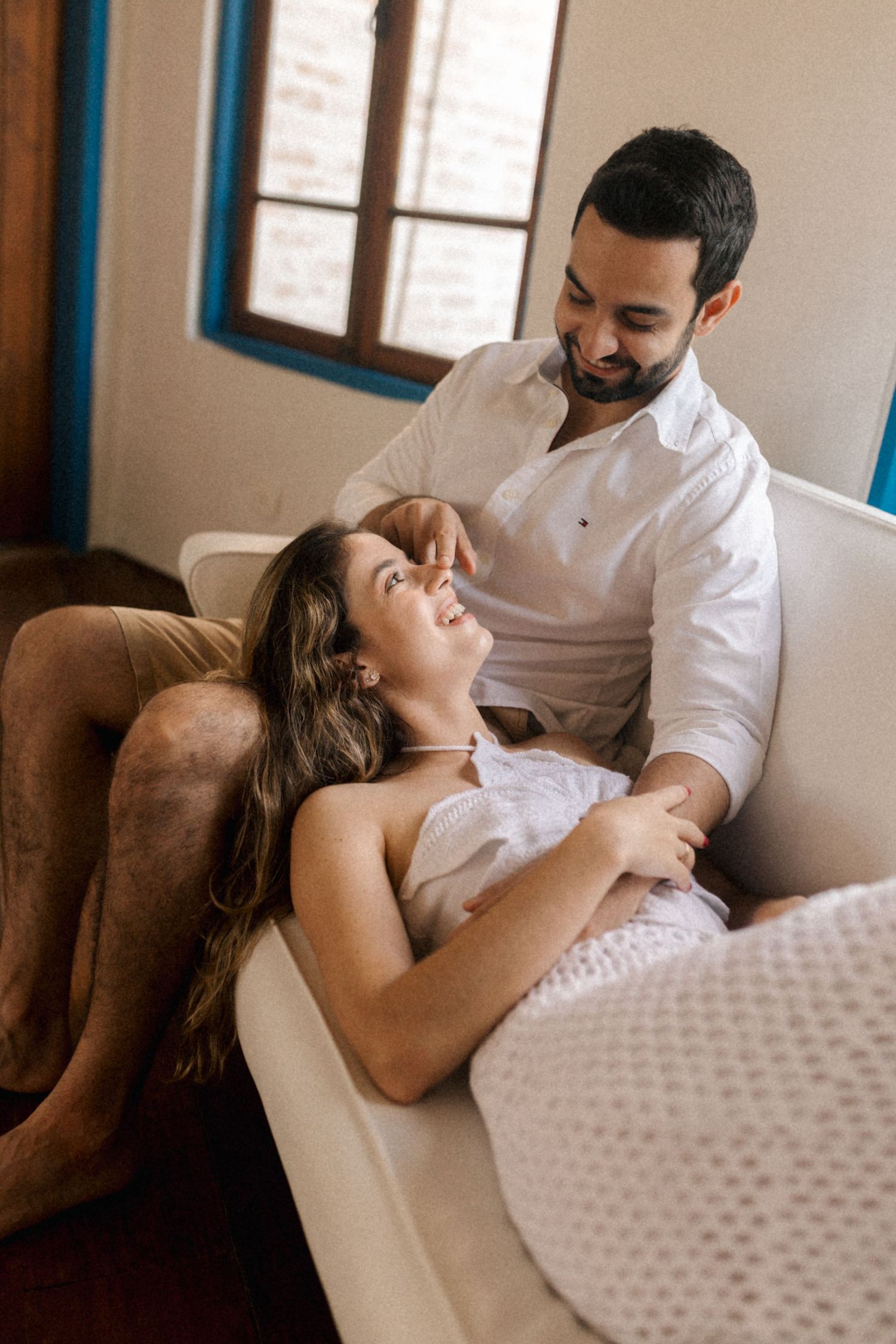 Couple sharing joyful laughter while relaxing on a cozy armchair.