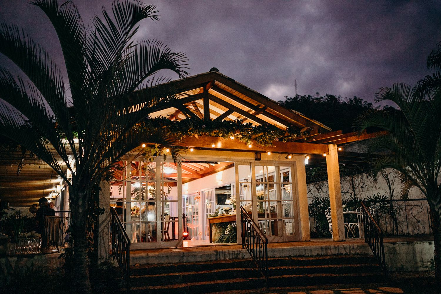 Illuminated outdoor pavilion with string lights glowing warmly against evening sky.
