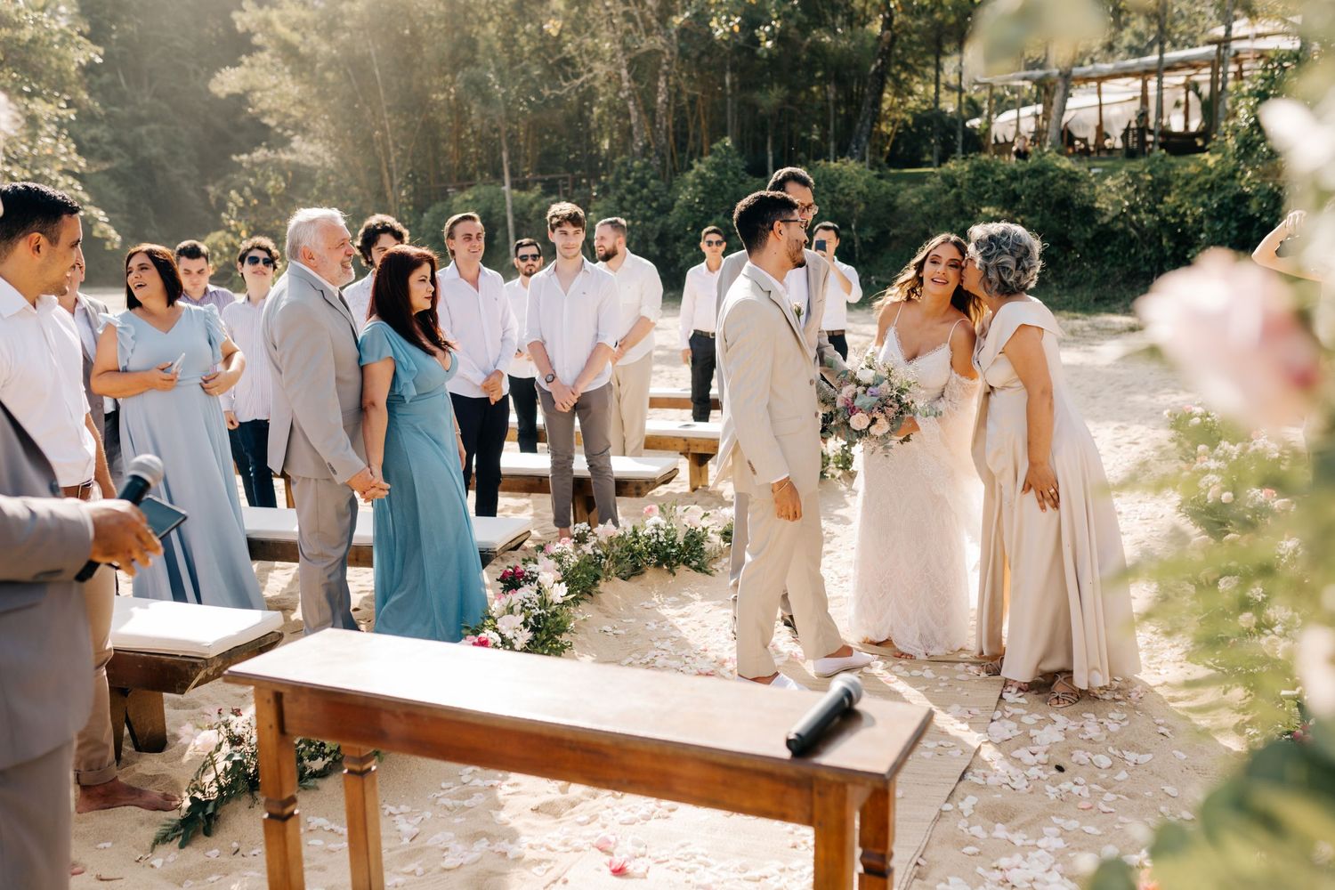 Wedding guests and wedding party gathered at sunny outdoor beach celebration.