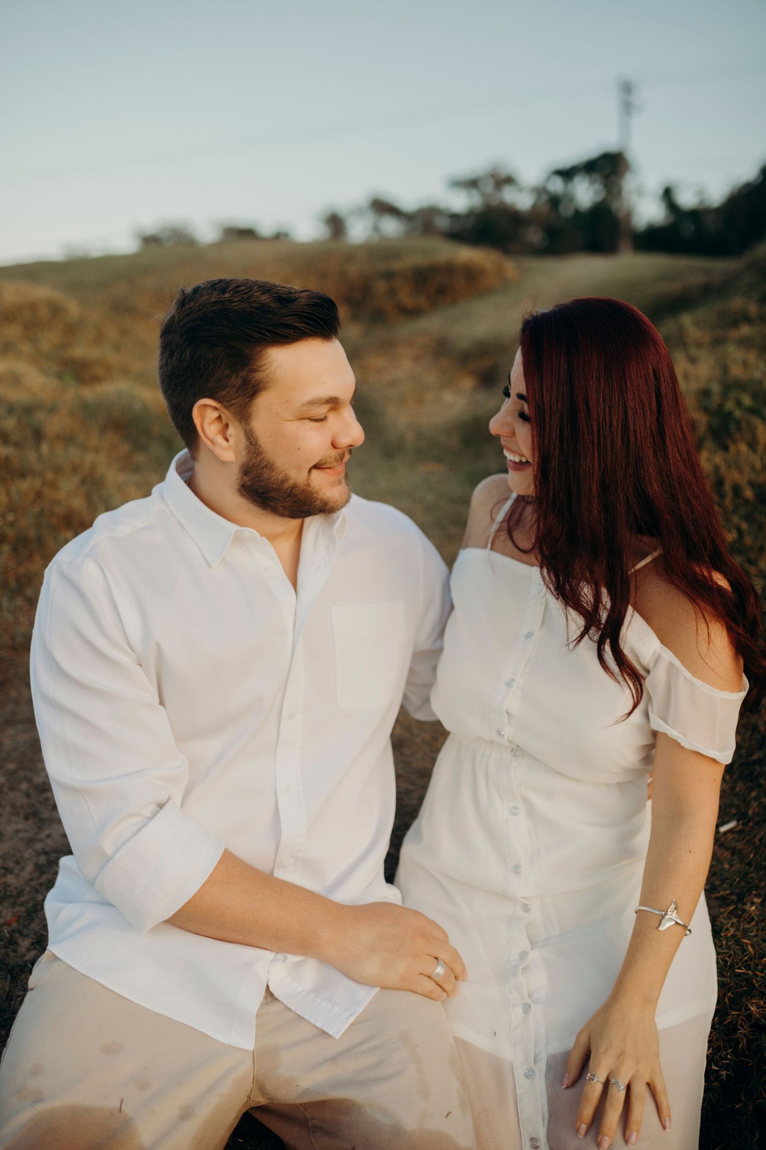 A couple shares a tender moment together on a hillside path at sunset.