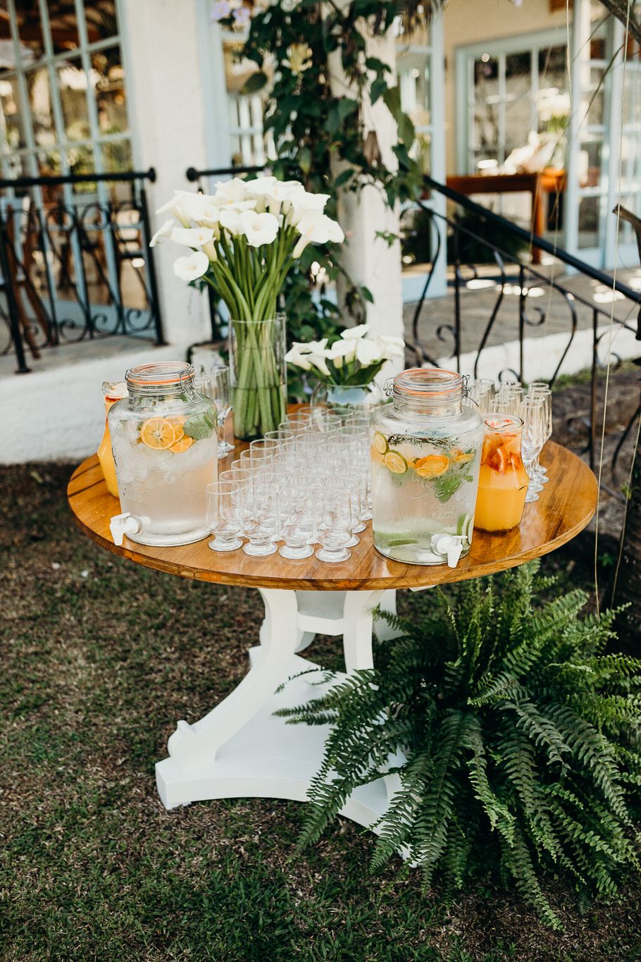 Elegant drink station setup with glass dispensers and floral arrangements on wooden tables.
