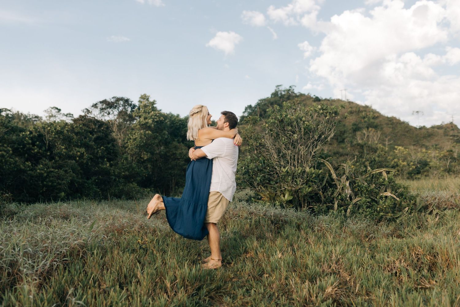 Couple enjoying a fun lifting moment in a scenic mountain meadow.