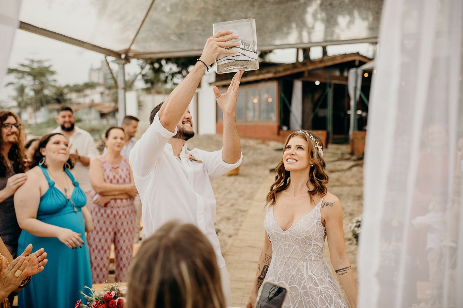 Wedding ceremony setup with white drapery and guests gathering outdoors.