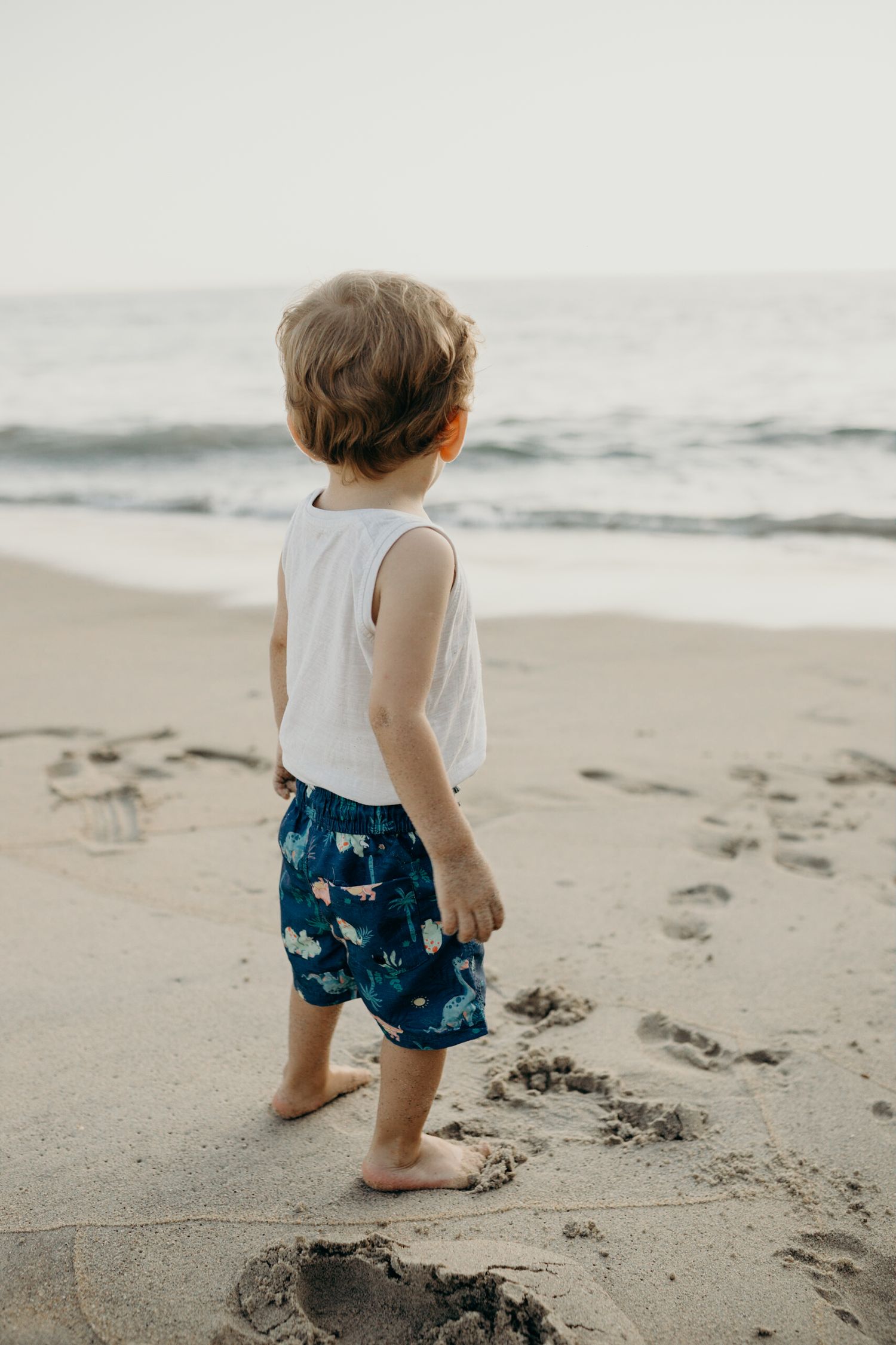 Small child's feet leaving footprints in the wet sand at the beach.