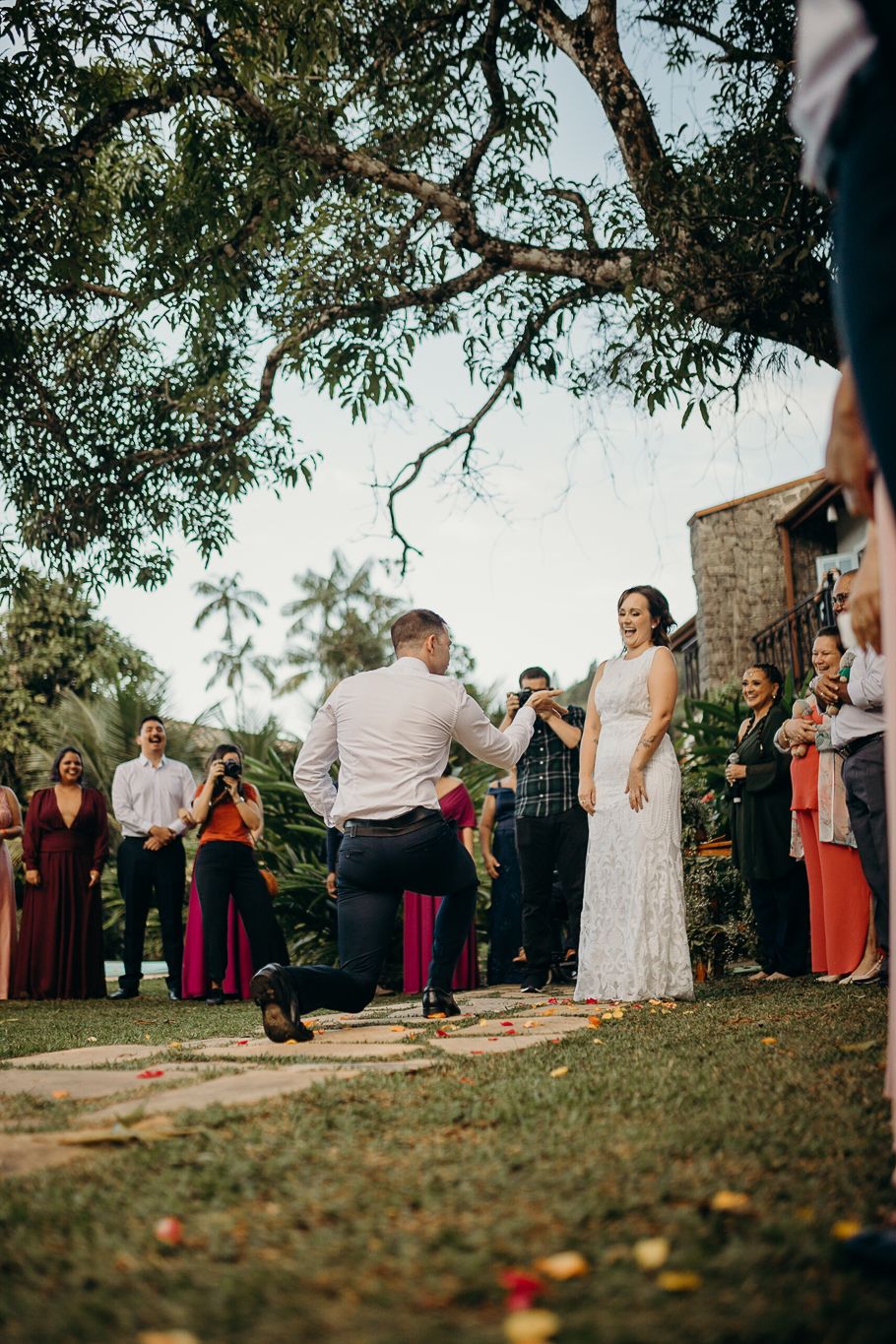 Special moment unfolds on stone pathway during outdoor ceremony surrounded by tropical landscaping.
