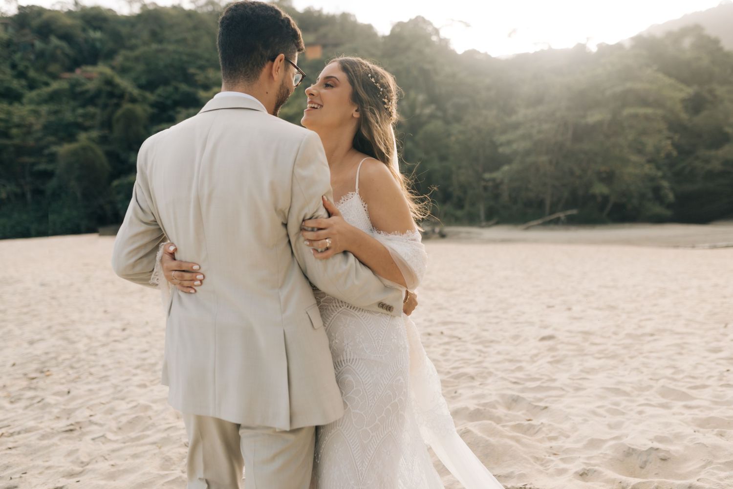 Intimate beach wedding moment with couple embracing during sunset.