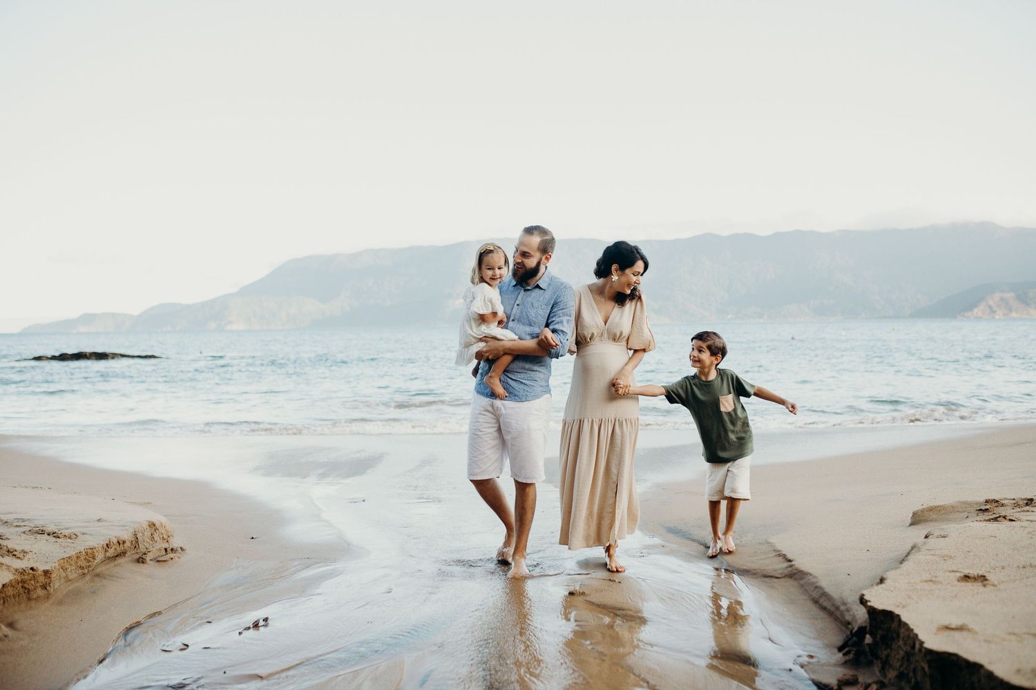 A scenic beach photoshoot with mountains and ocean in the background.