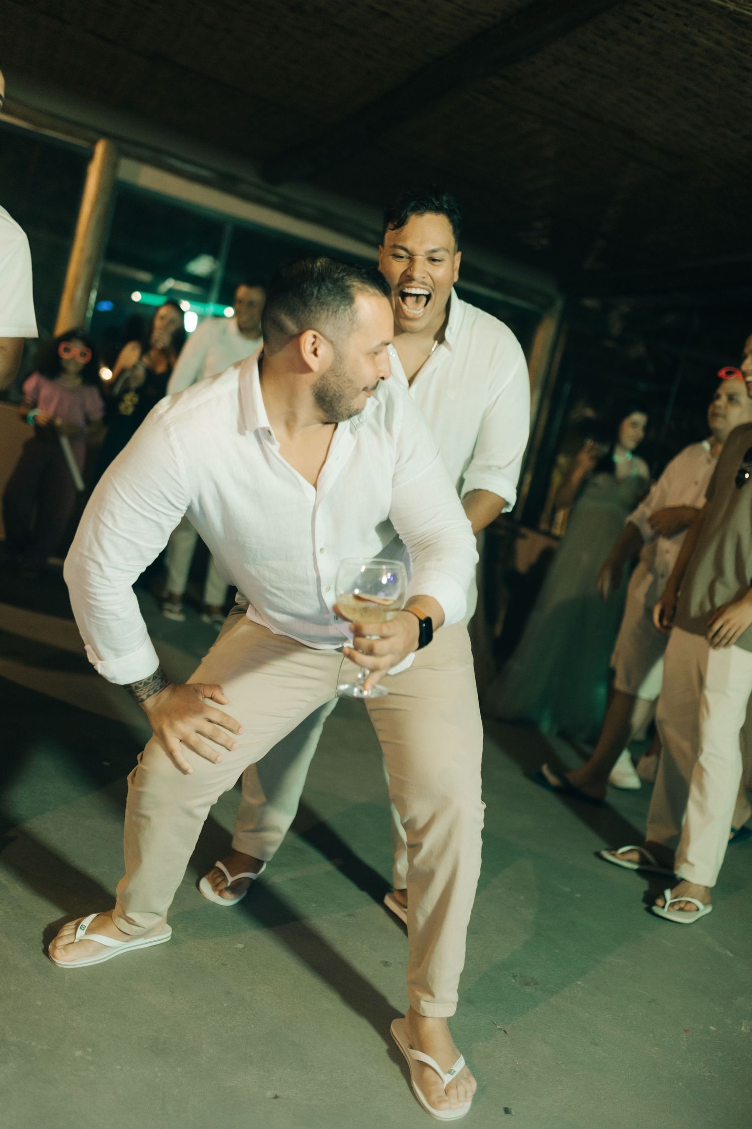 Two guests share a laugh while dancing at dimly lit wedding reception.
