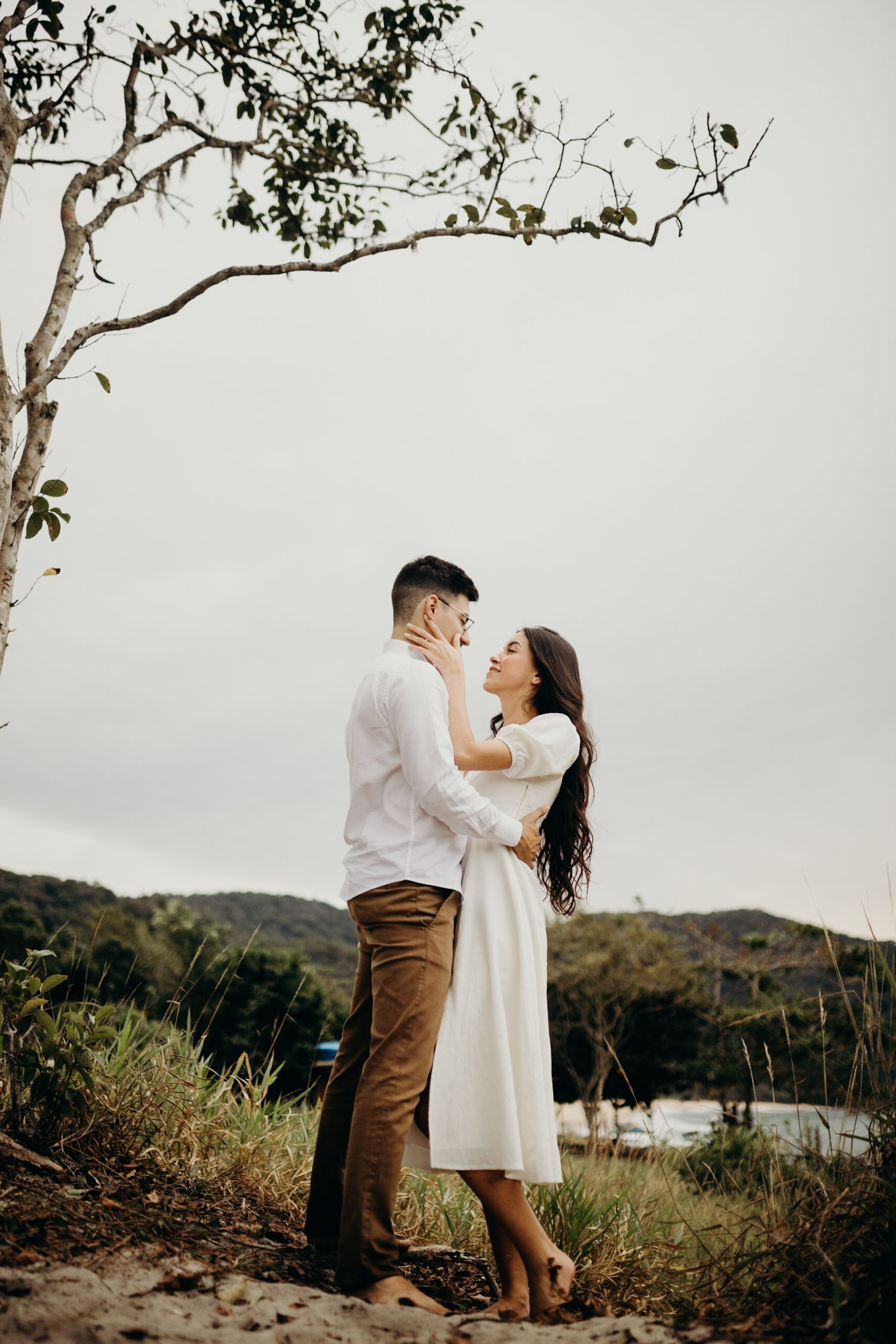 Romantic couple poses affectionately against a scenic coastal landscape.