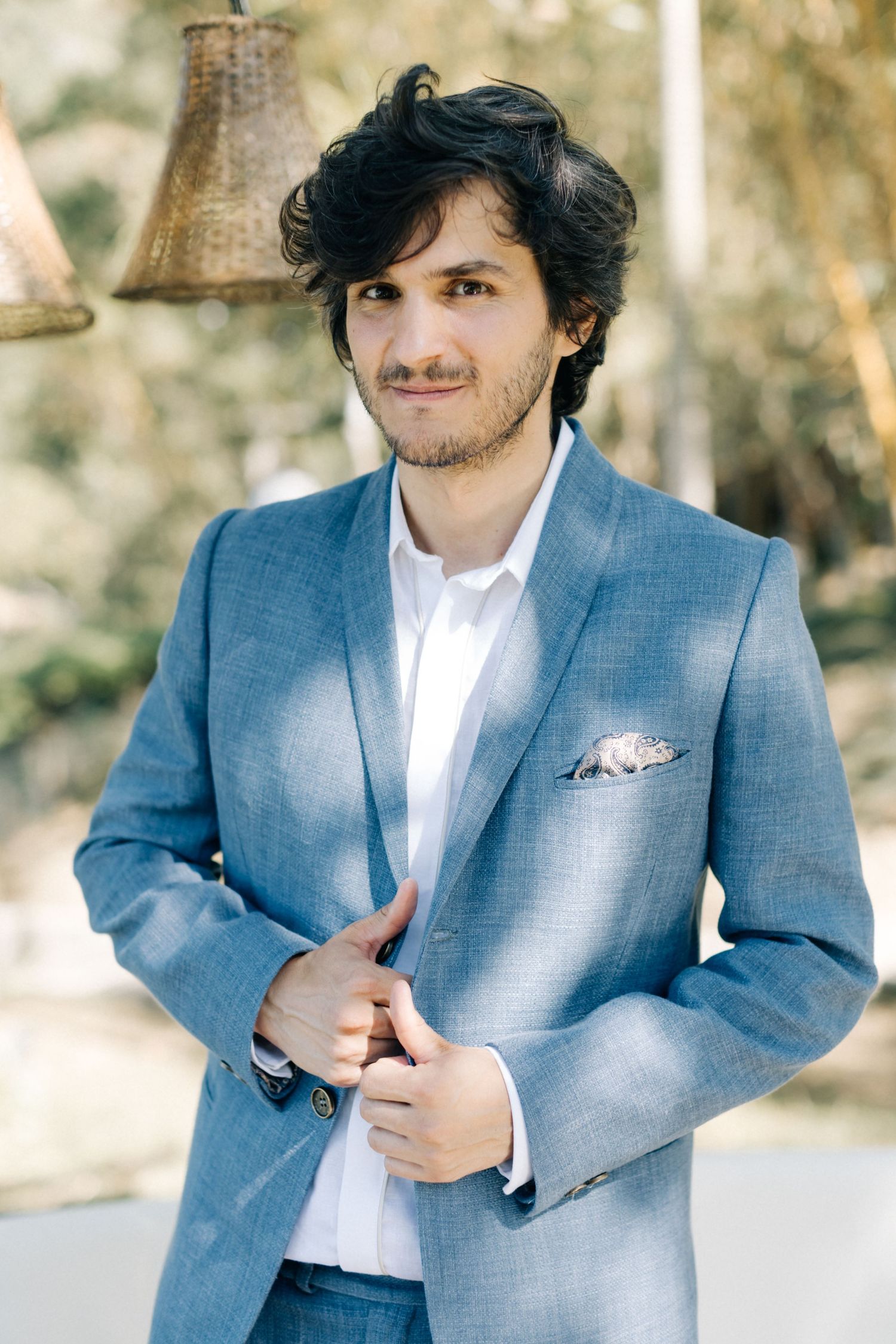 A close-up portrait showing someone in a tailored blue blazer outdoors.