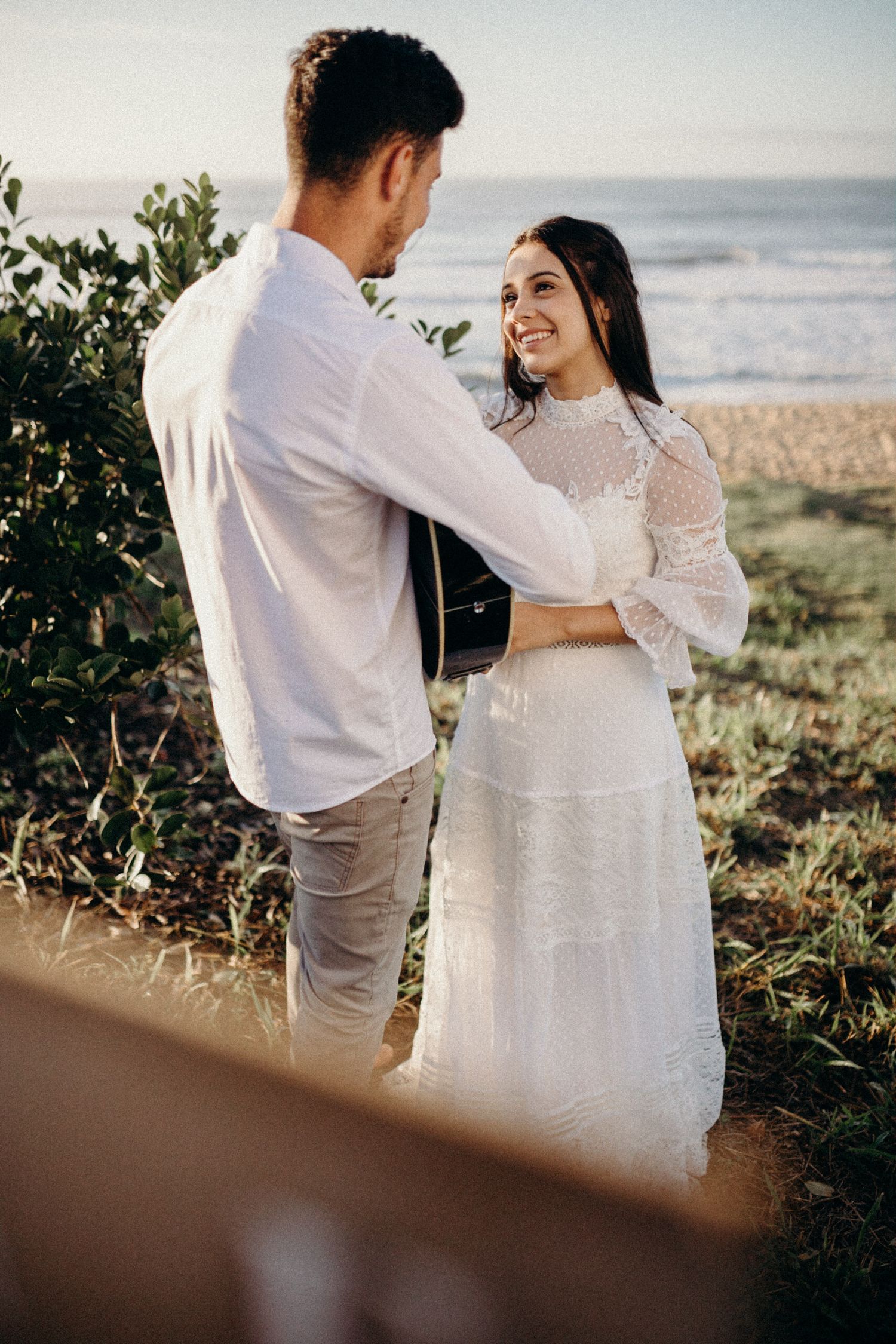 Couple shares tender moment during coastal wedding photoshoot.
