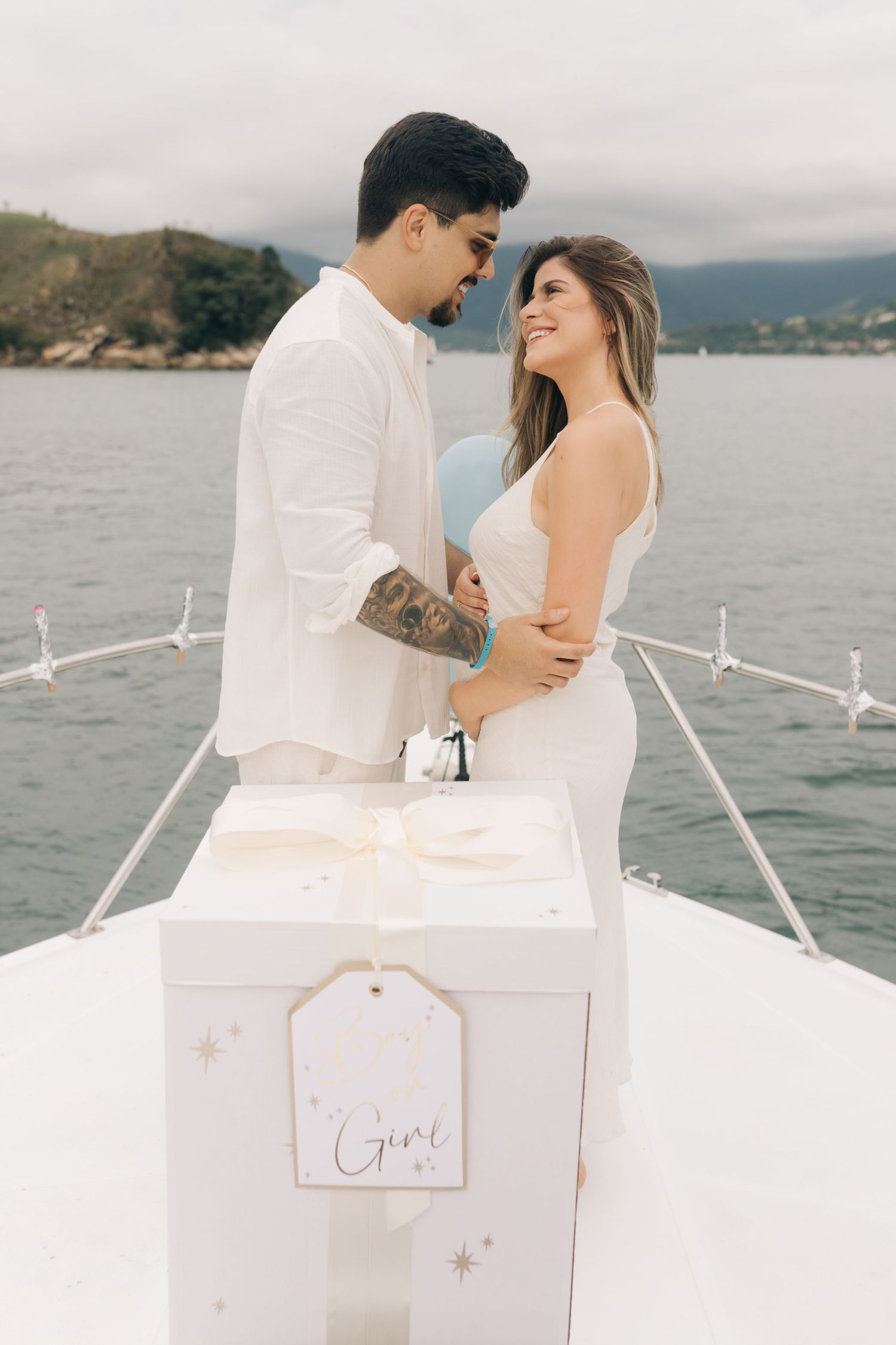 Intimate moment shared on yacht deck with coastal mountains in background.