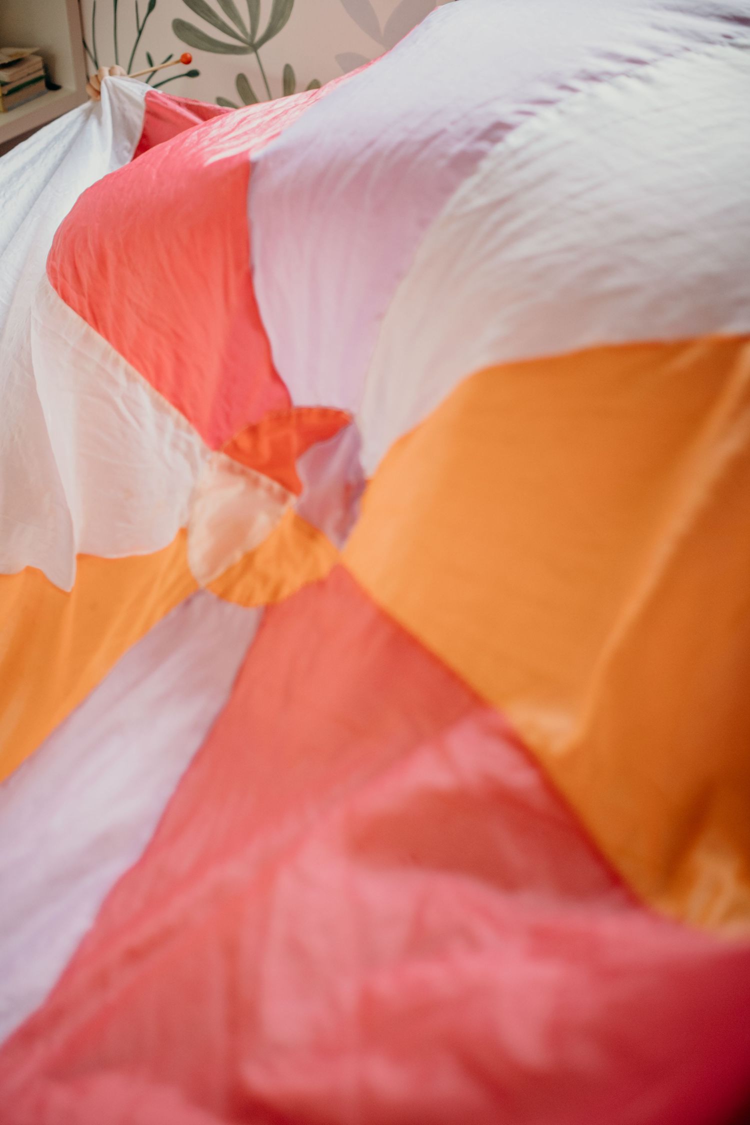 Close-up of colorful bedding in coral, orange, and white tones with a delicate fabric texture.