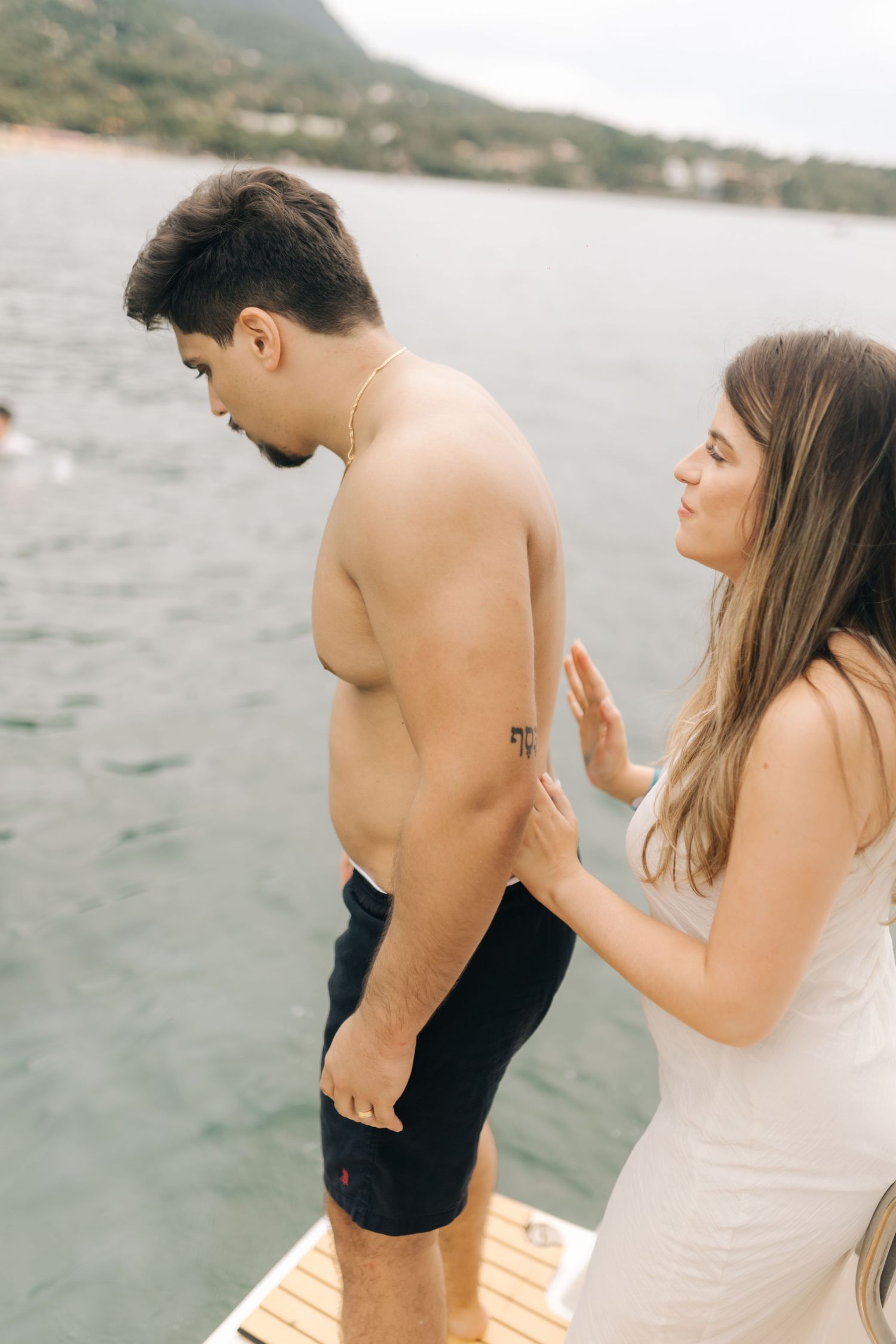 Two people preparing to jump off wooden boat deck into ocean water.