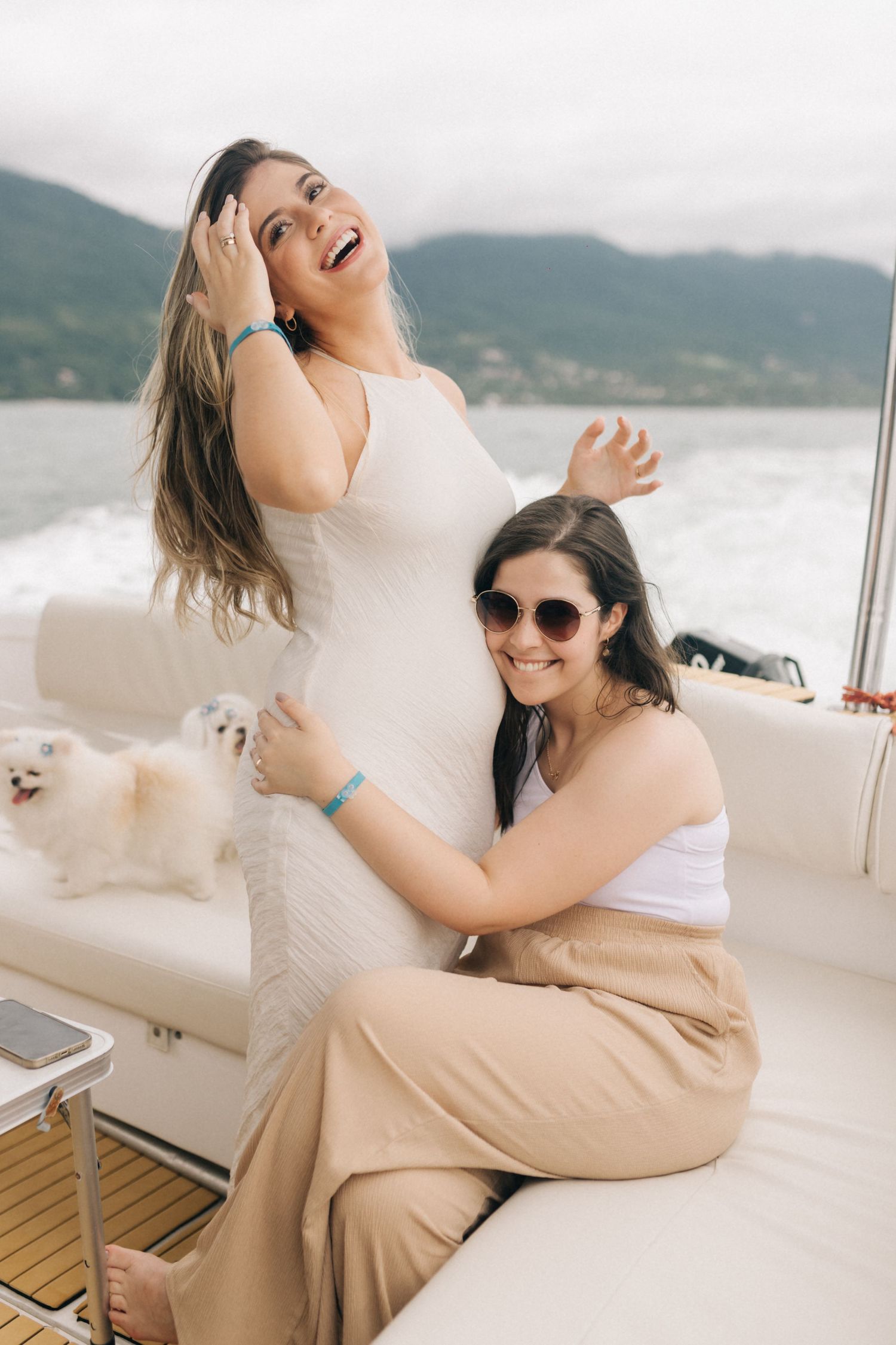 Friends sharing joyful moments on yacht deck with coastal scenery.