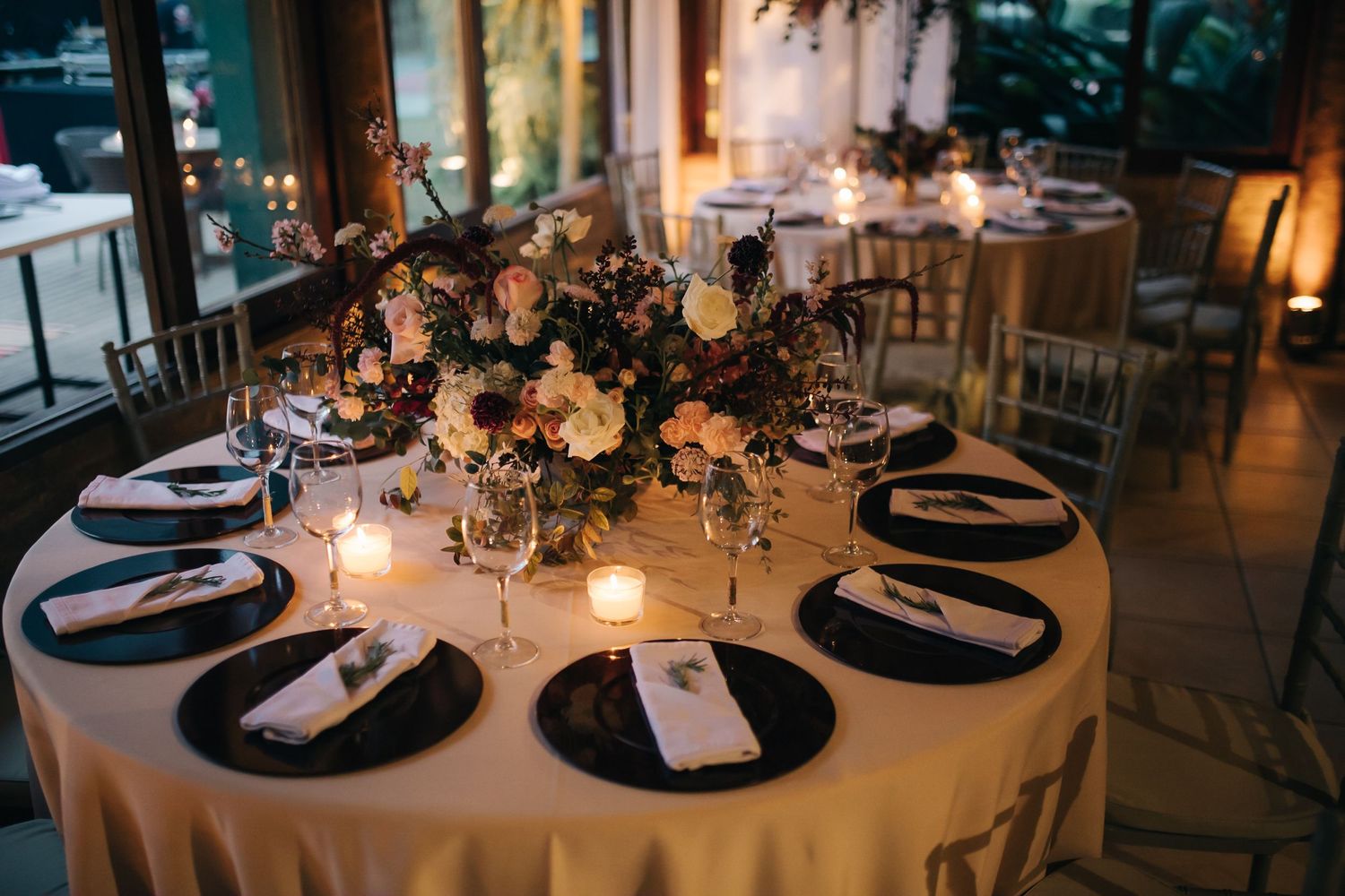 Candlelit wedding reception tables with elegant place settings and ambient lighting.