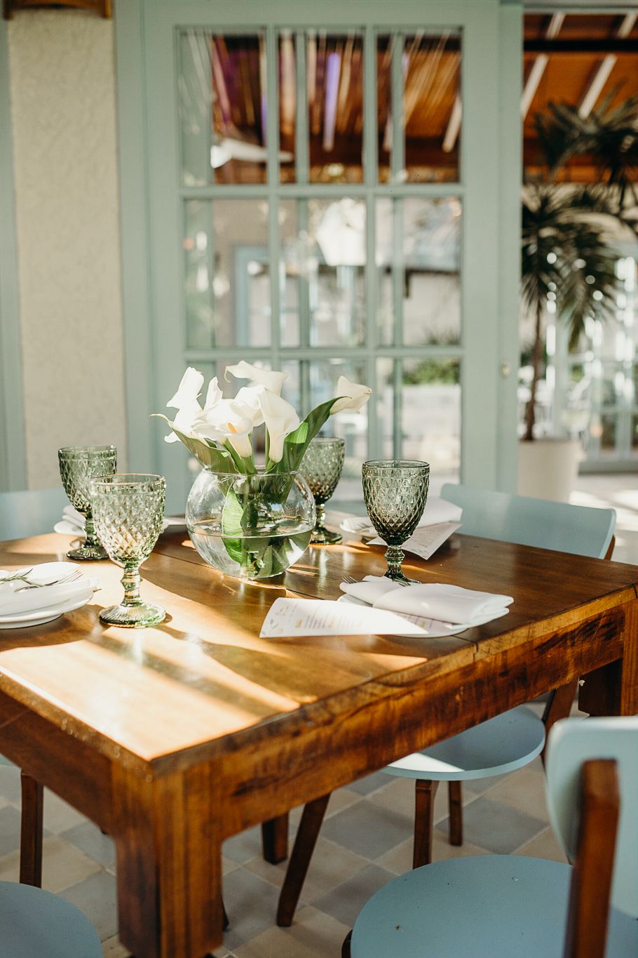 Intimate table setting with crystal glasses, white flowers, and warm wood furniture.