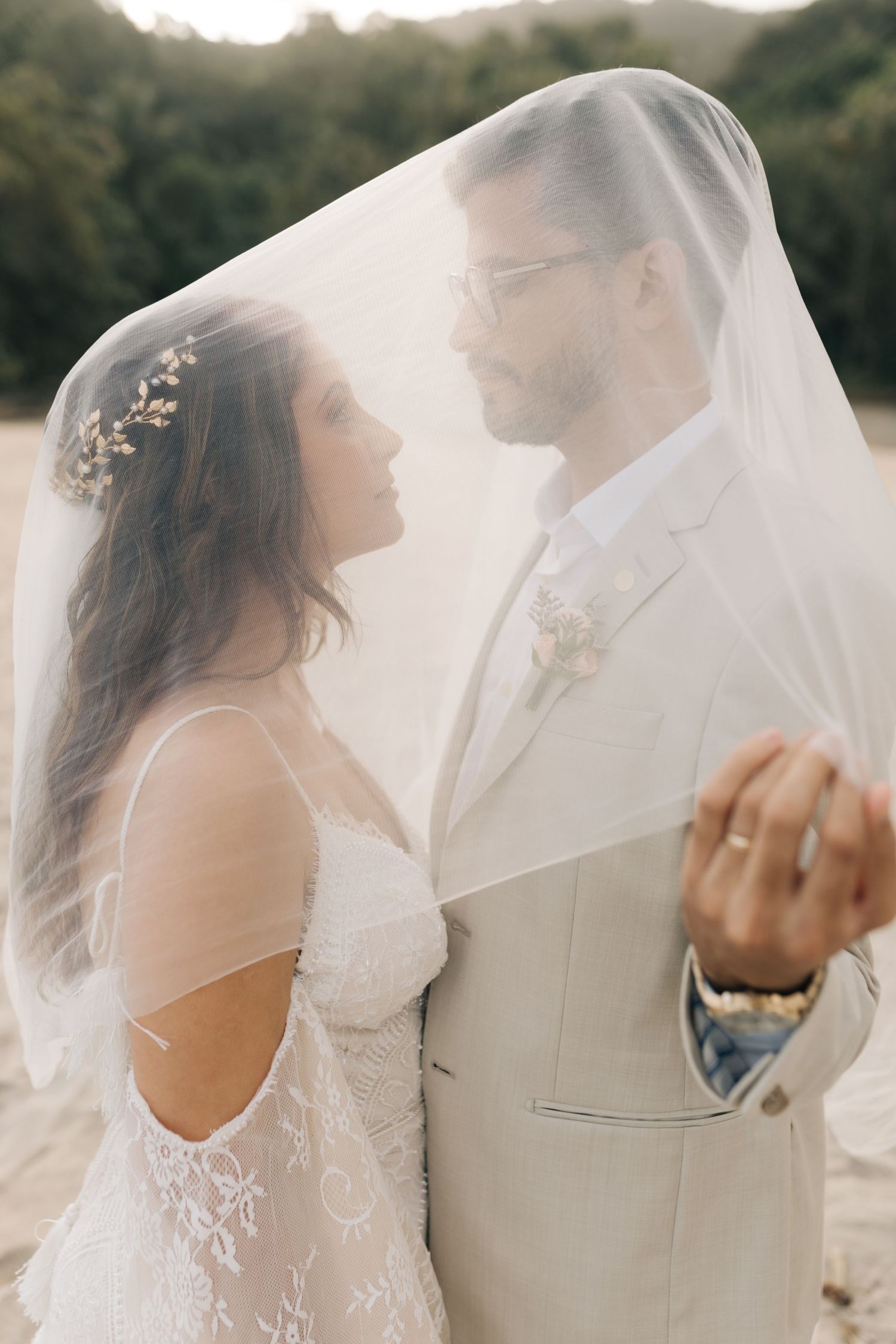Elegant beach wedding portrait with couple sharing an intimate dance beneath a flowing veil.