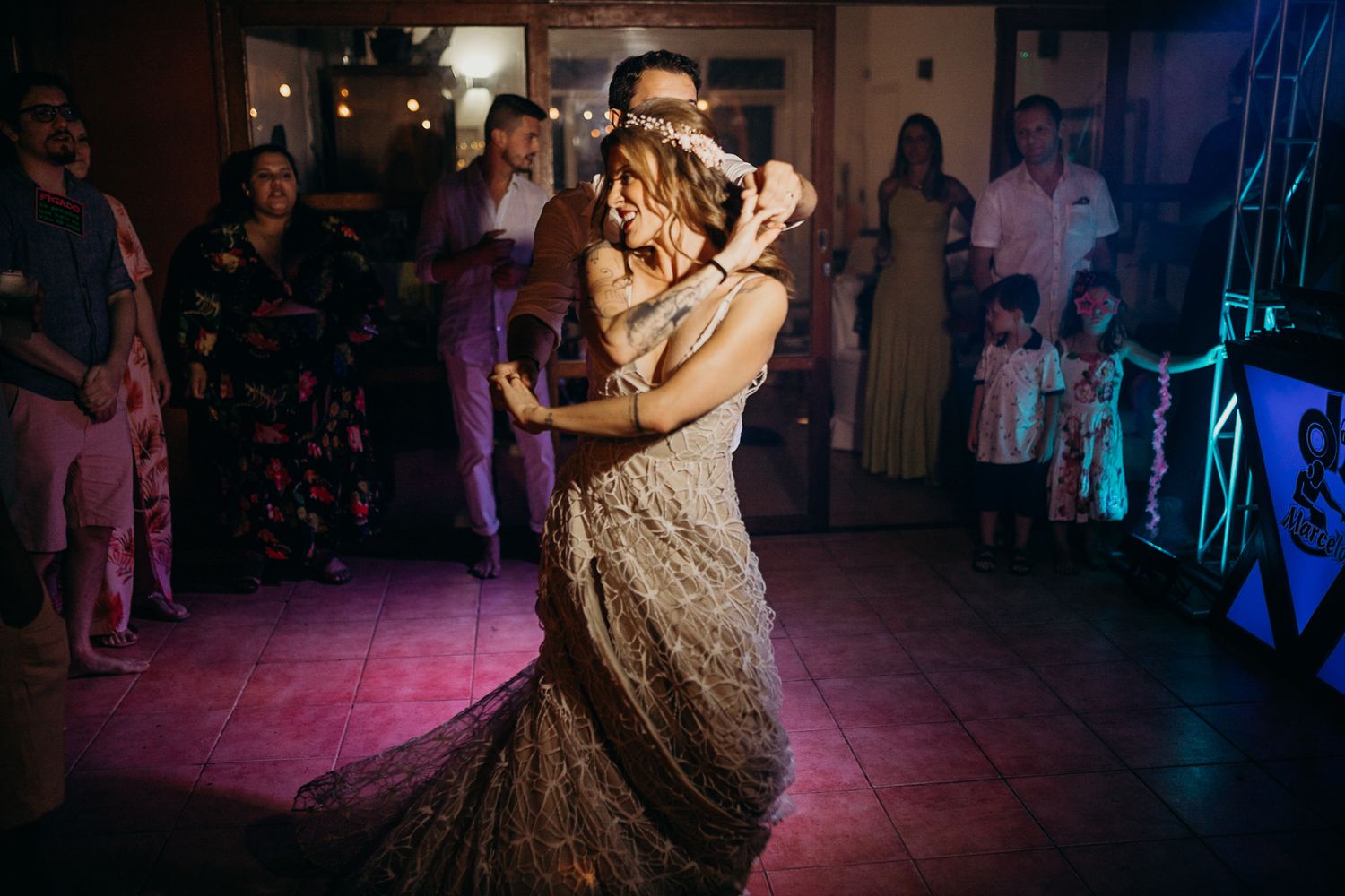 Couples dancing together during a dimly lit wedding reception with purple mood lighting.
