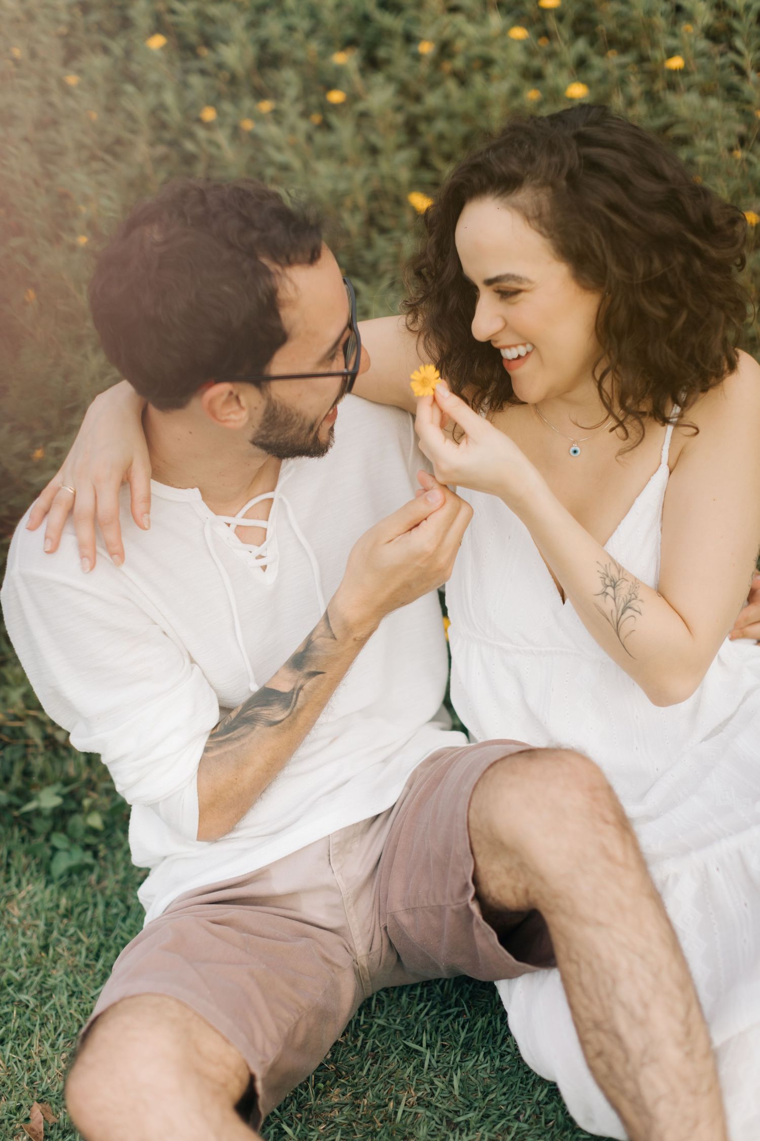 Sweet candid moments between couple laying in grass during outdoor photo session.