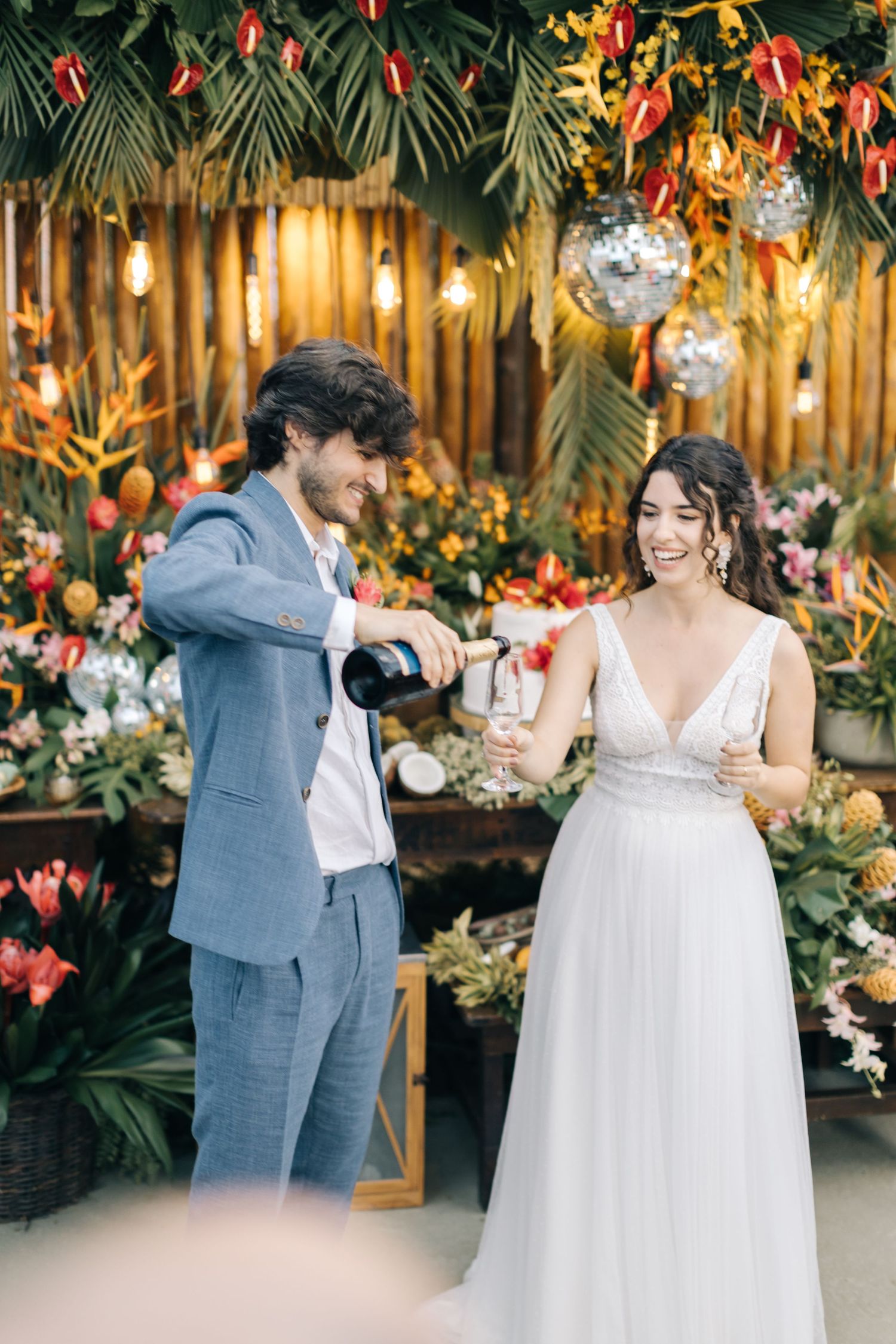 Champagne toast moment at wedding reception with tropical floral backdrop.