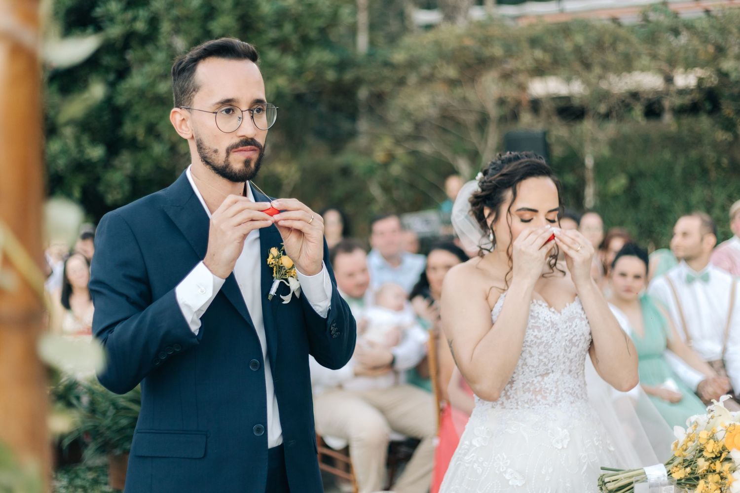 Couple shares a candid emotional moment during their wedding ceremony outdoors.