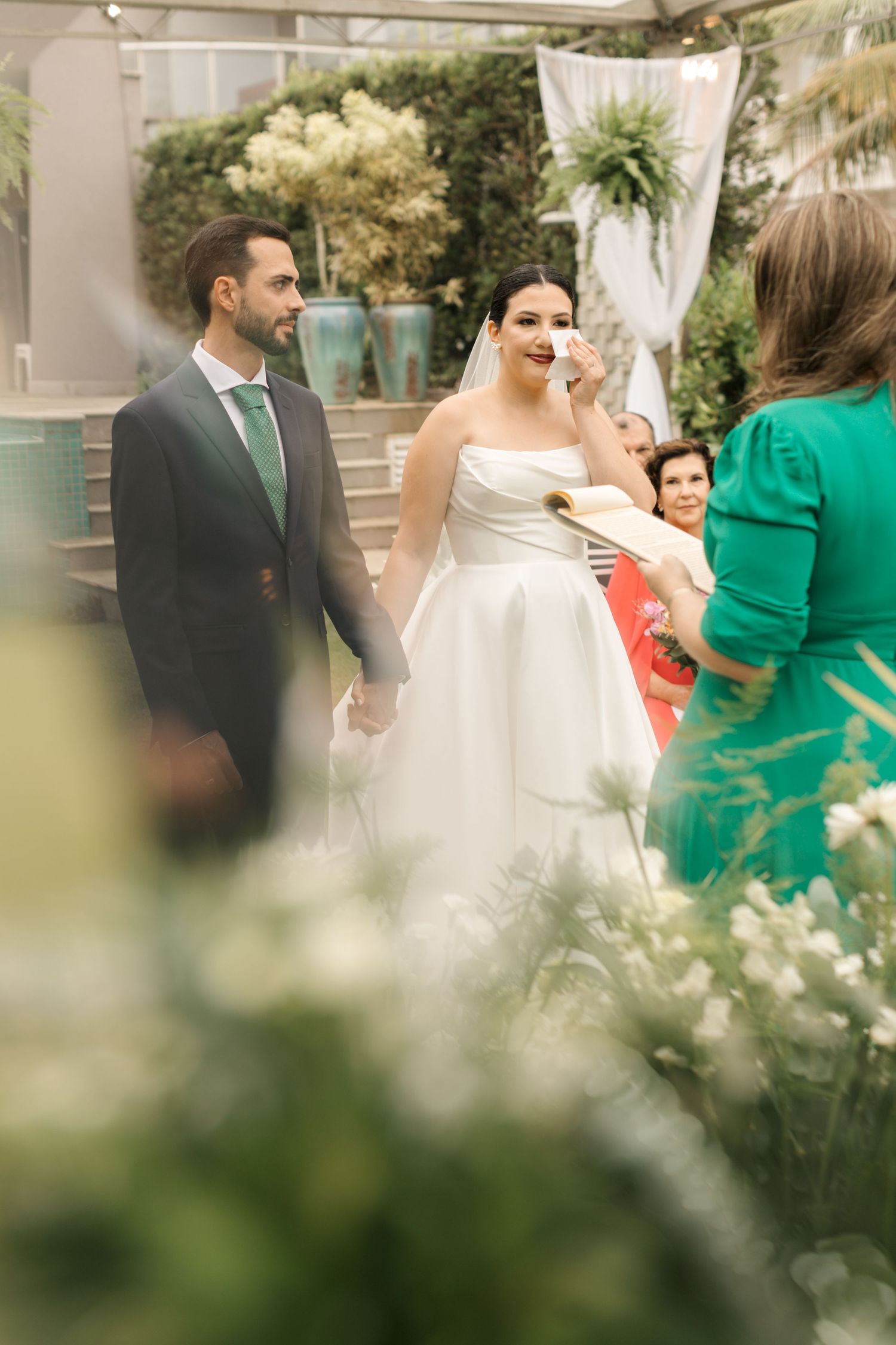 Intimate garden wedding ceremony with greenery and white floral arrangements.
