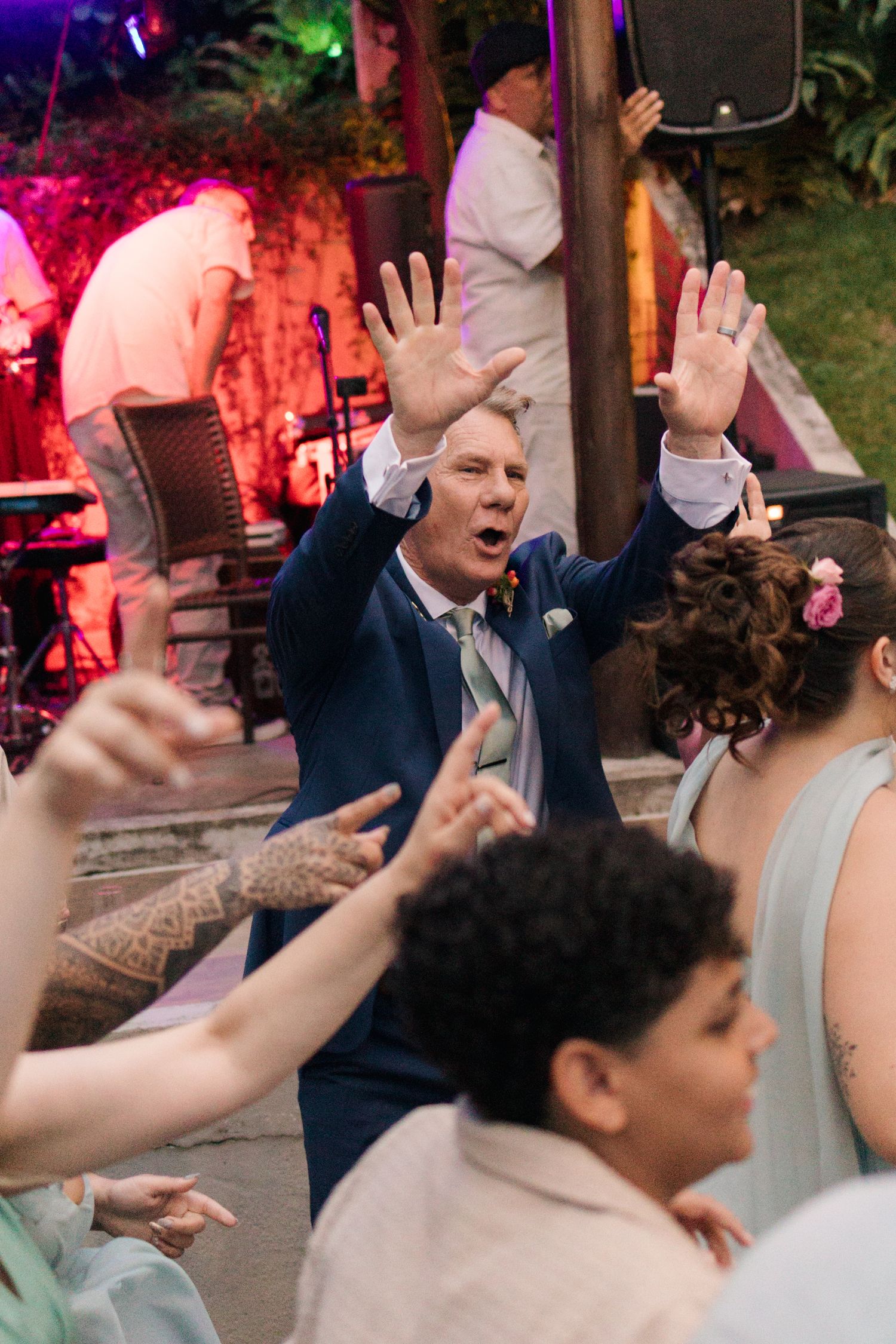 Wedding reception dance party with colorful pink and purple lighting creating a festive atmosphere.