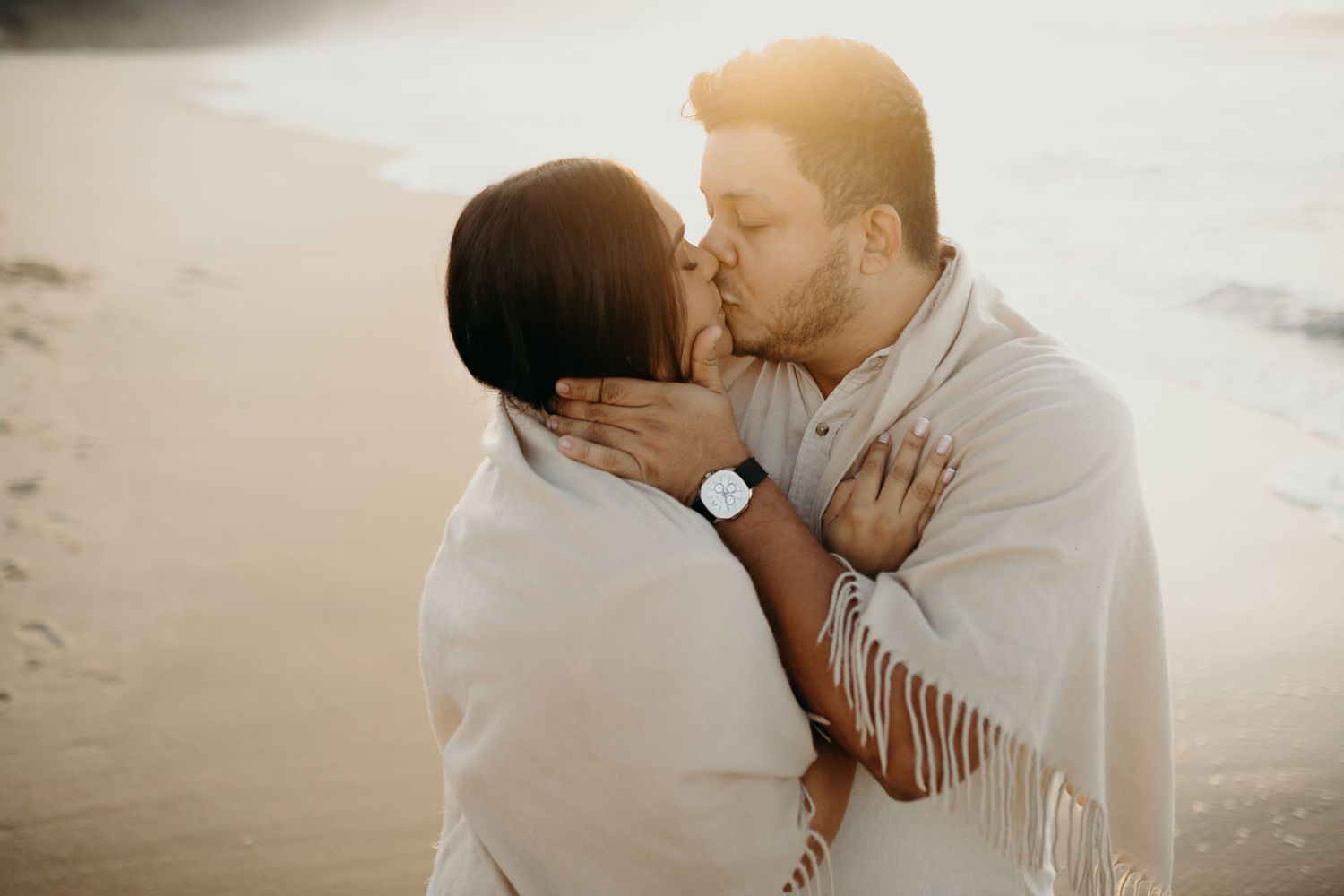 Intimate beach portraits of couple sharing romantic moments at sunset.