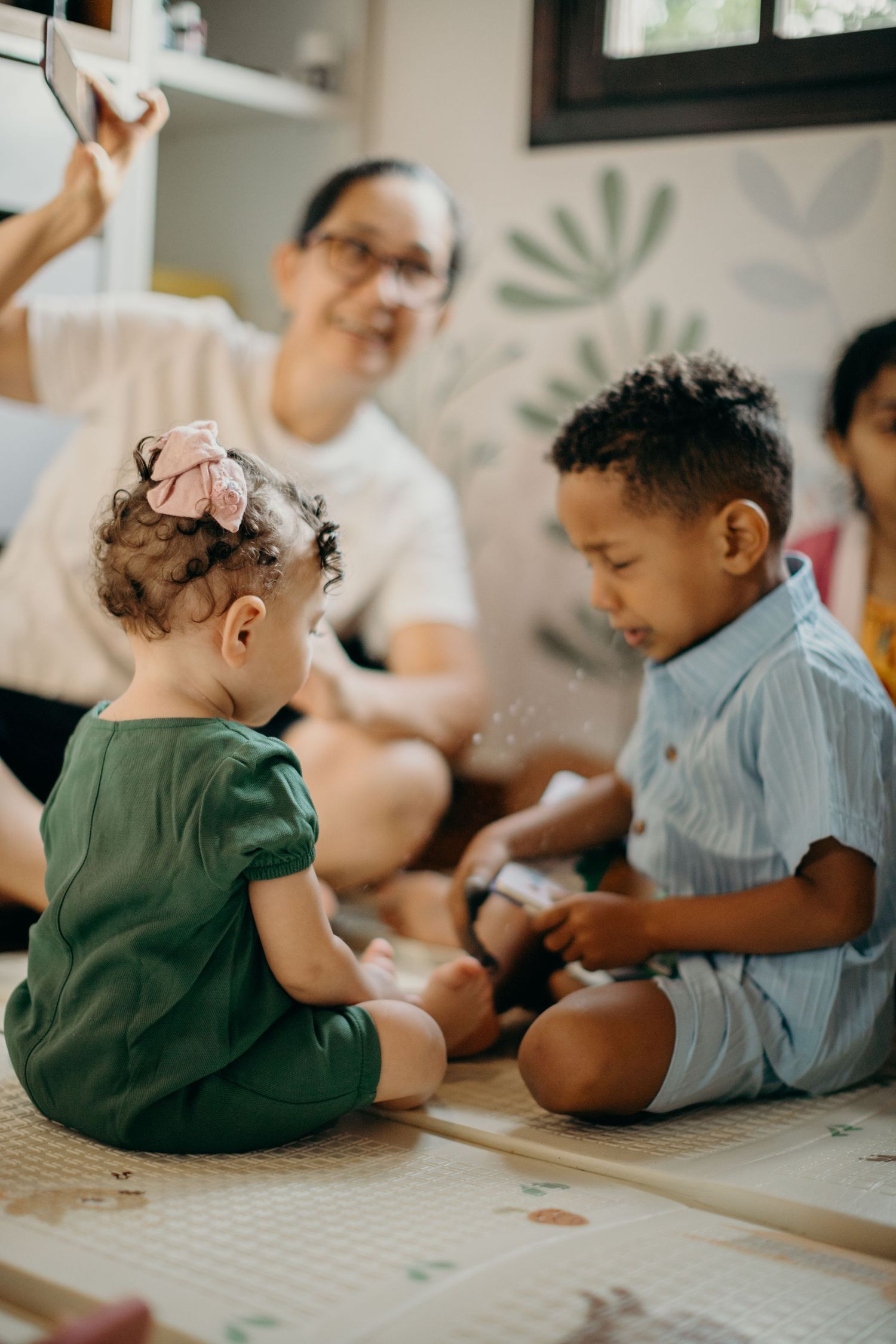 Young children sitting on floor engaging with educational materials.