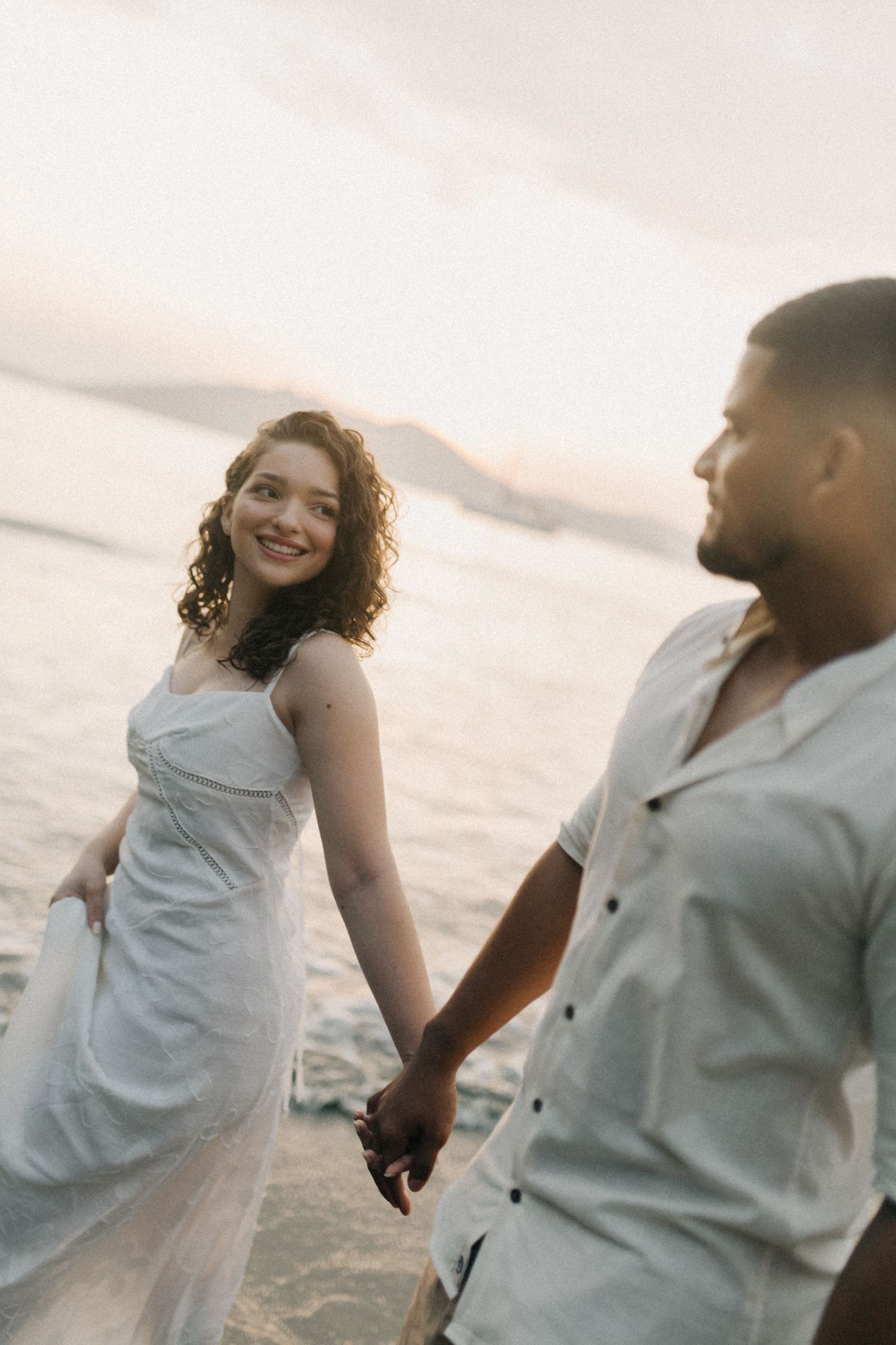 Couple sharing a joyful moment together on a beach during golden hour.
