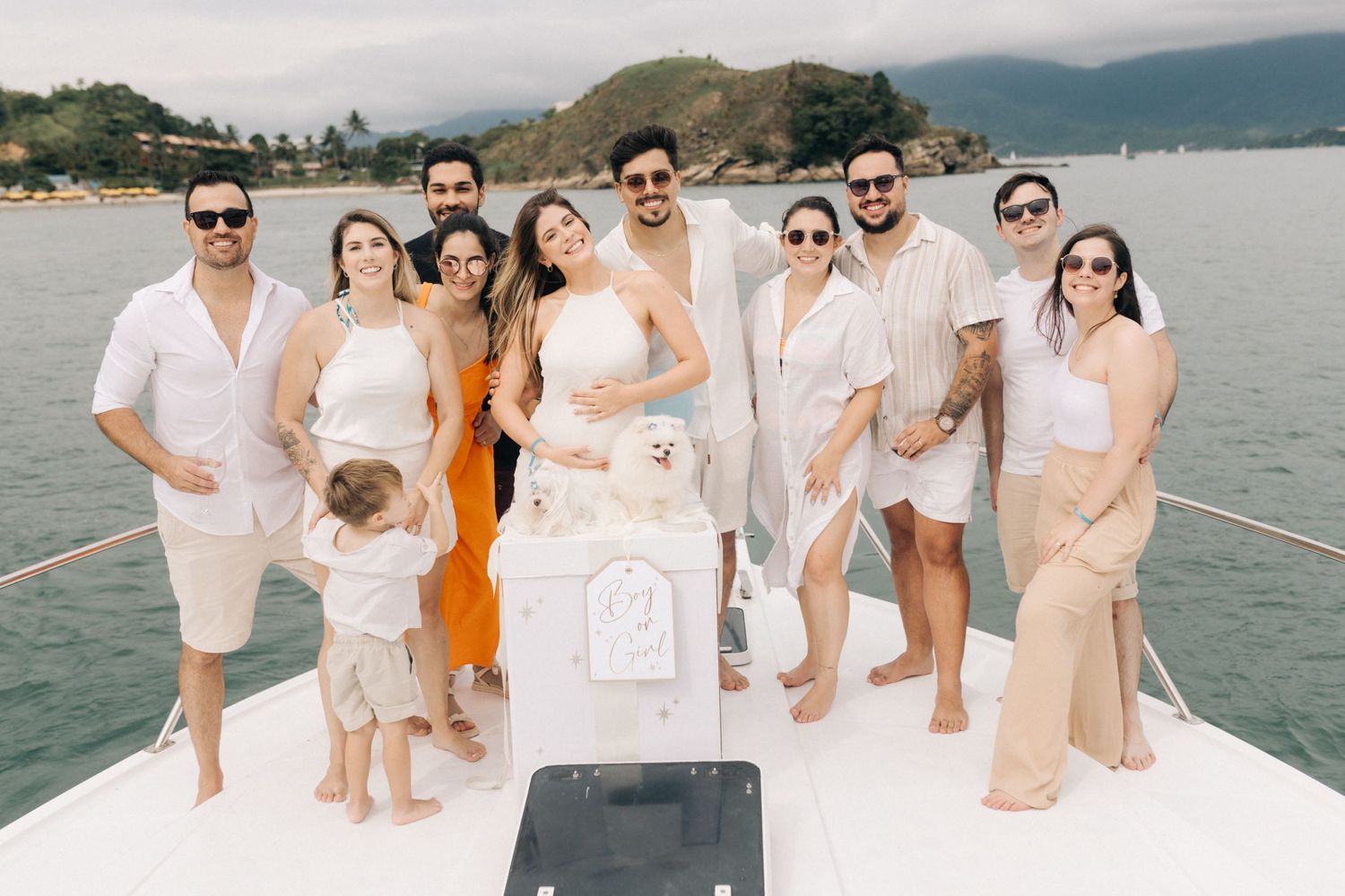 A group dressed in white and beige poses together on a boat for a gender reveal party.