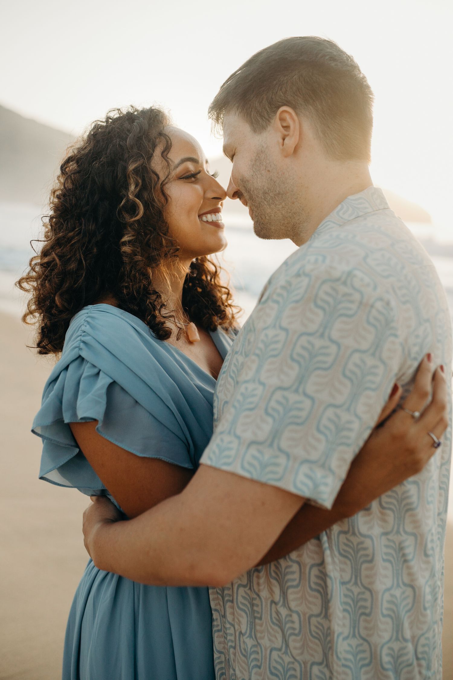 Happy couple embracing on beach with sunset lighting.